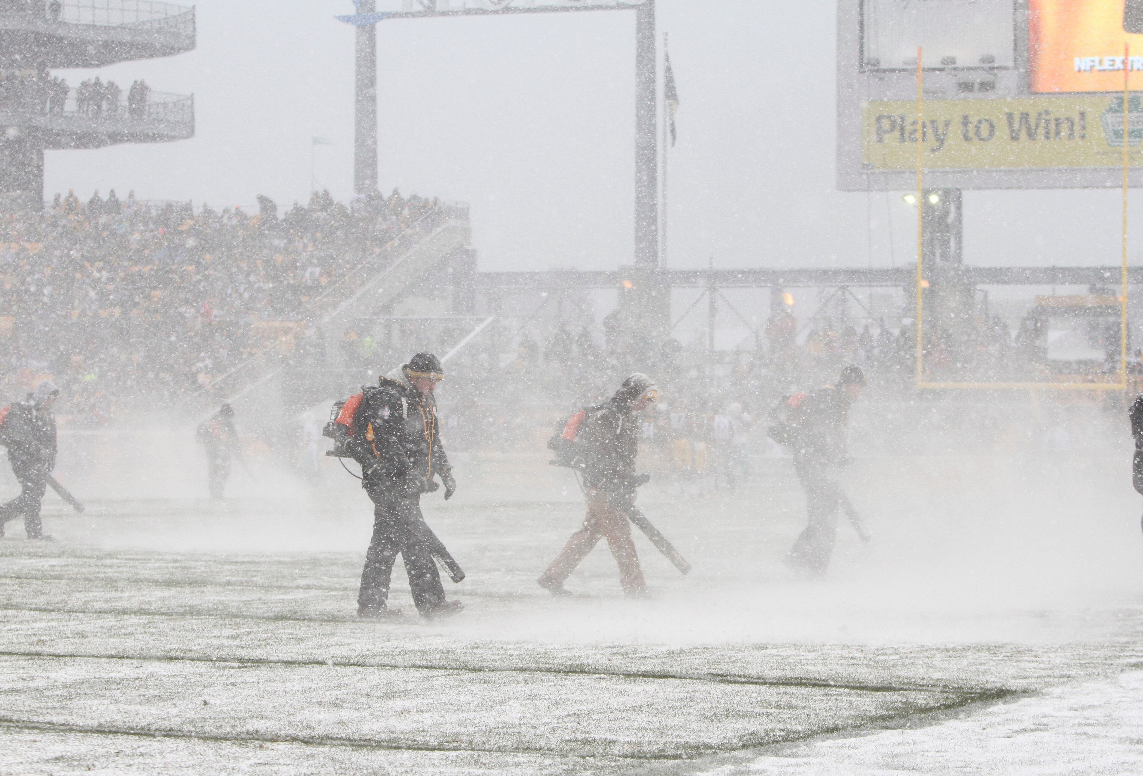 Heinz Field field crews blow the snow off of the yard lines during a break in the Pittsburgh Steelers and Miami Dolphins game in the first half at Heinz Field.