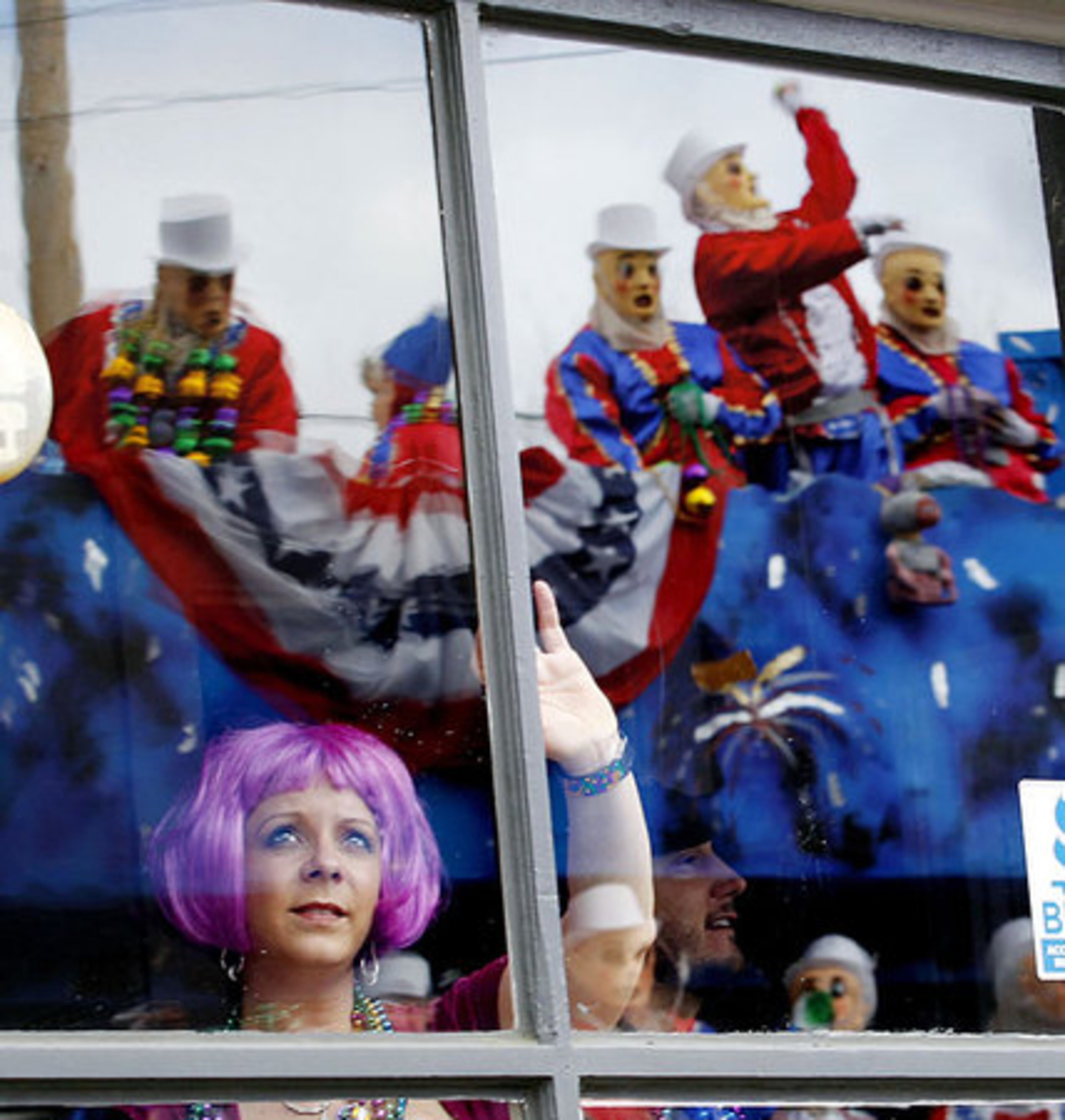Jaqueline Mortenson watches through a window the passing Thoth parade as it reflects its 65th anniversary ride, which chose "Streets of New Orleans" as its theme, Sunday, Feb. 19, 2012 in New Orleans.