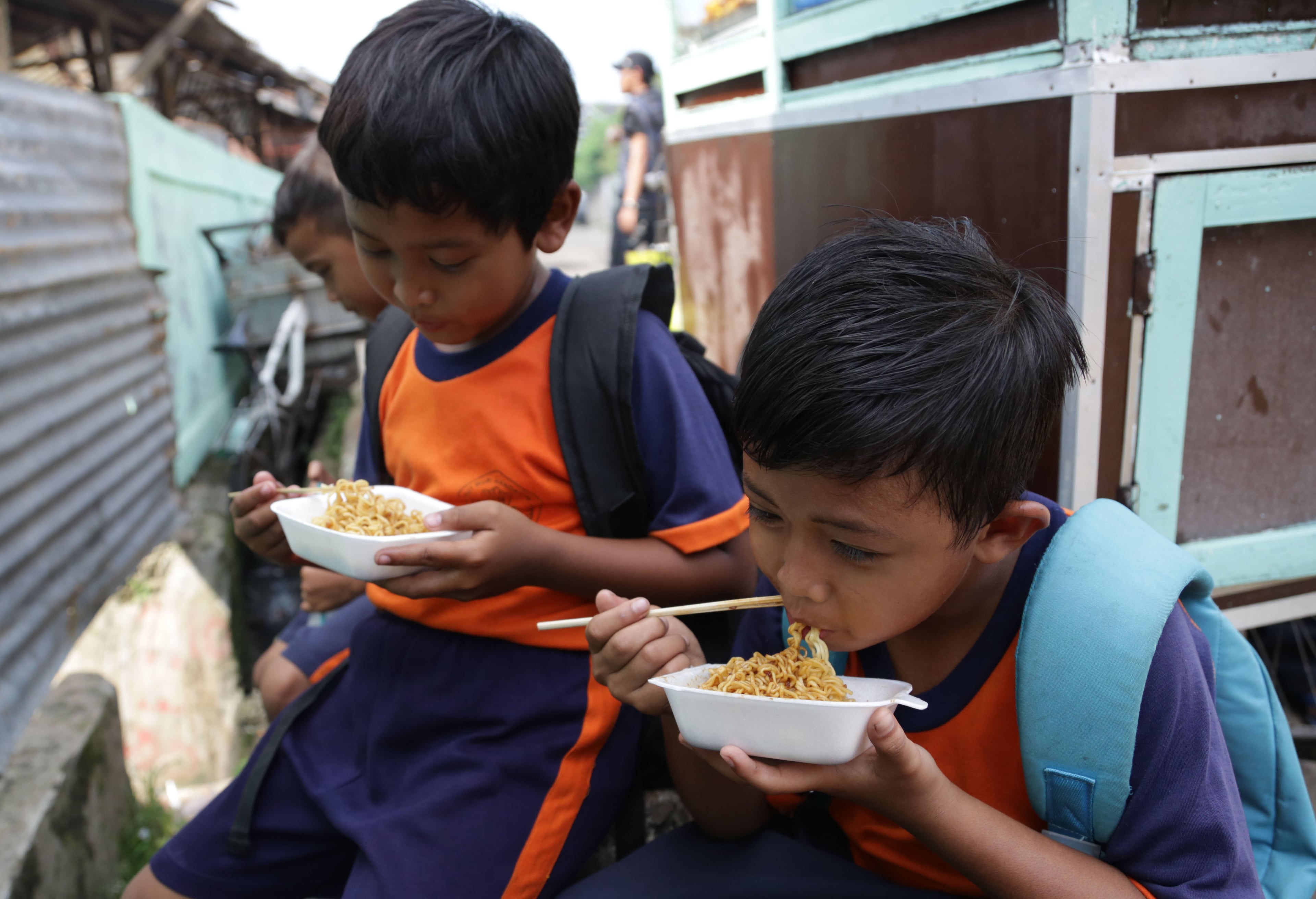 Public elementary school children eat noodles on a street after school in Jakarta, Indonesia, Tuesday, May 6, 2014. In Indonesia not every student can bring lunch box to school. Public school students buy their lunch at school cafeterias or food stalls on streets nearby. One plate of noodles costs about 3 cents. (AP Photo/Achmad Ibrahim)