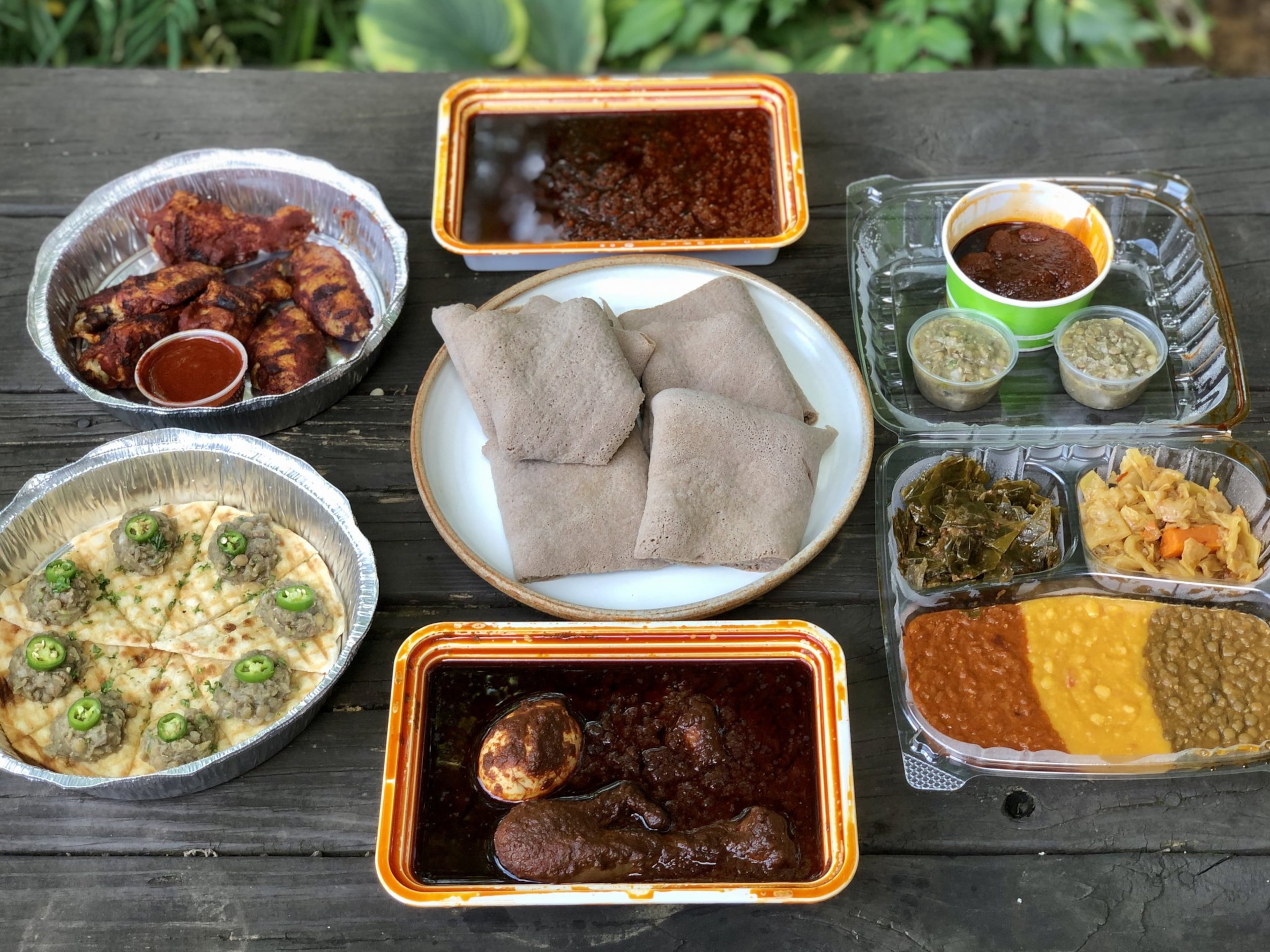 This takeout feast from Feedel Bistro features (clockwise from upper left): awaze wings; minchet abish key wet; vegan sampler; doro wet; azifah on pita; and injera (center). CONTRIBUTED BY WENDELL BROCK