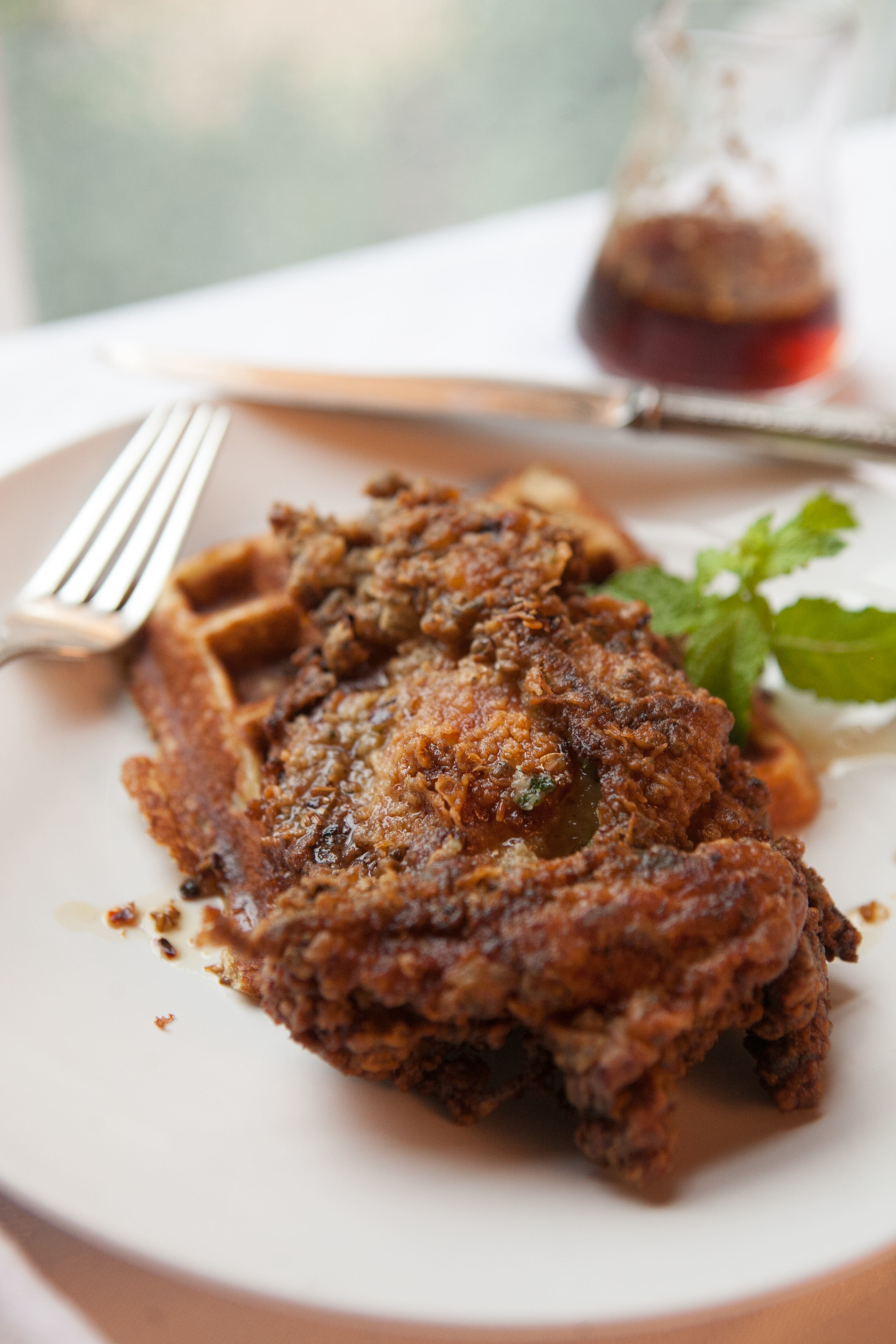 Asha Gomez's Keralan Fried Chicken, Lowcountry Cardamom Waffles and Spicy Maple Syrup. Atlanta chef Asha Gomez created this rich, complex dish at her first Atlanta restaurant, Cardamom Hill, which closed recently. A play on the cuisines of her native Kerala in the south of India and her more recent home in the American South, the dish requires more than 24 hours to prepare; the recipe is included in Lee Brian Schrager's book "Fried & True: More Than 50 Recipes for America's Best Fried Chicken and Sides" (Clarkson Potter, $22.50). (styling by Wendell Brock) (Photography by Renee Brock/Special)