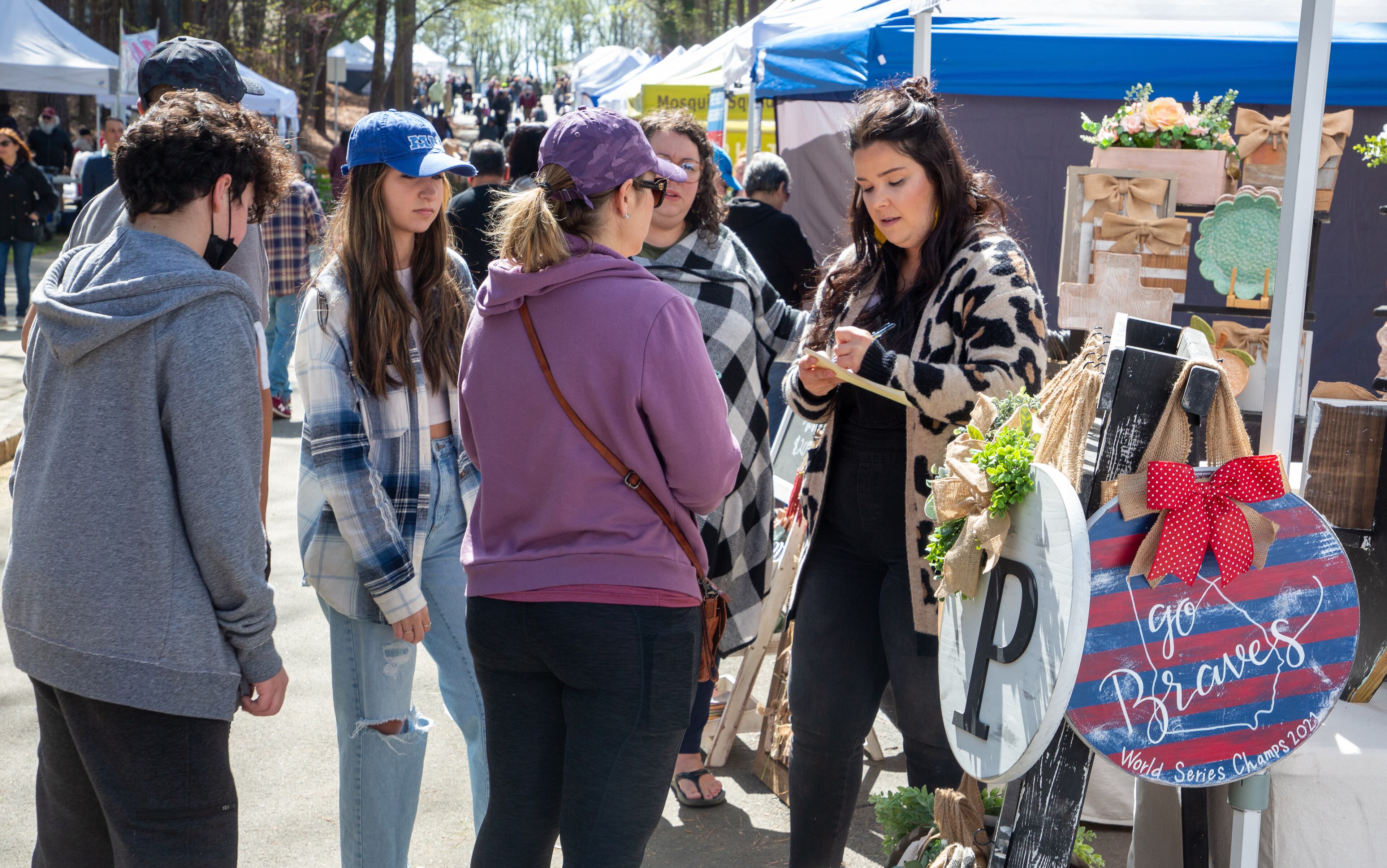 Stary Turner (right) takes an order at her artist tent during the Brookhaven Cherry Blossom Festival in Blackburn Park on Sunday, March 27, 2022. STEVE SCHAEFER FOR THE ATLANTA JOURNAL-CONSTITUTION