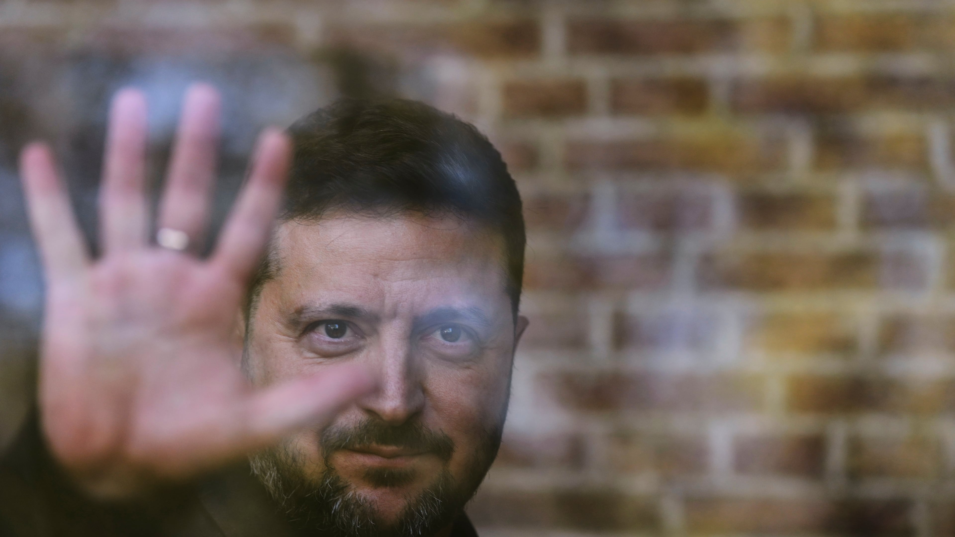 Ukraine's President Volodymyr Zelenskyy waves from behind a glass window after he received the Freedom Medal of the International Four Freedoms Award during a ceremony in Middelburg, Netherlands, Thursday, April 16, 2026. (AP Photo/Peter Dejong)