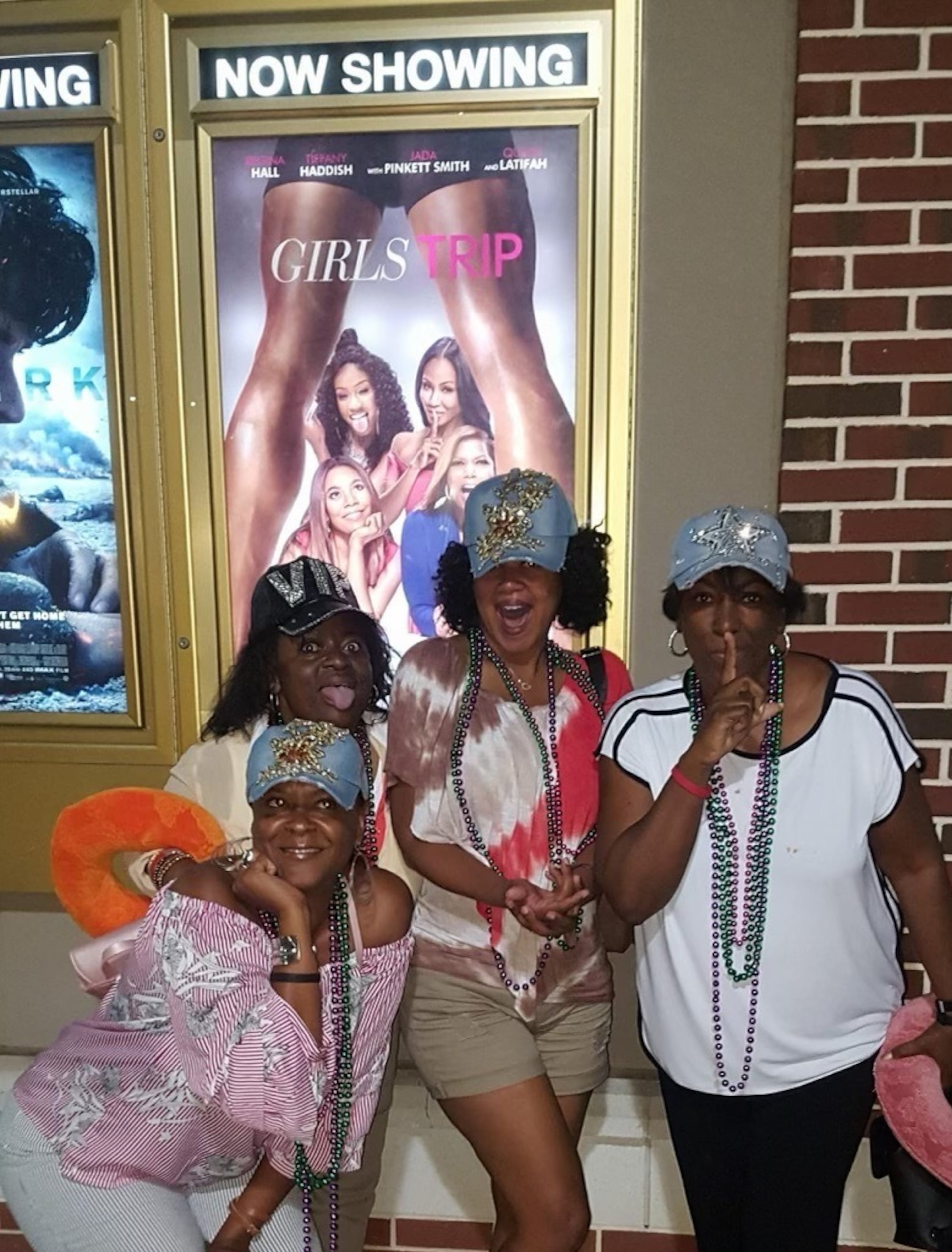 Lisa Haygood, Shelia Howell-Reynolds, Tonya Hood and Tonya Mahone Williams pose beneath a poster for the movie, "Girls Trip," about four Black women who travel to New Orleans for the Essence Festival. “