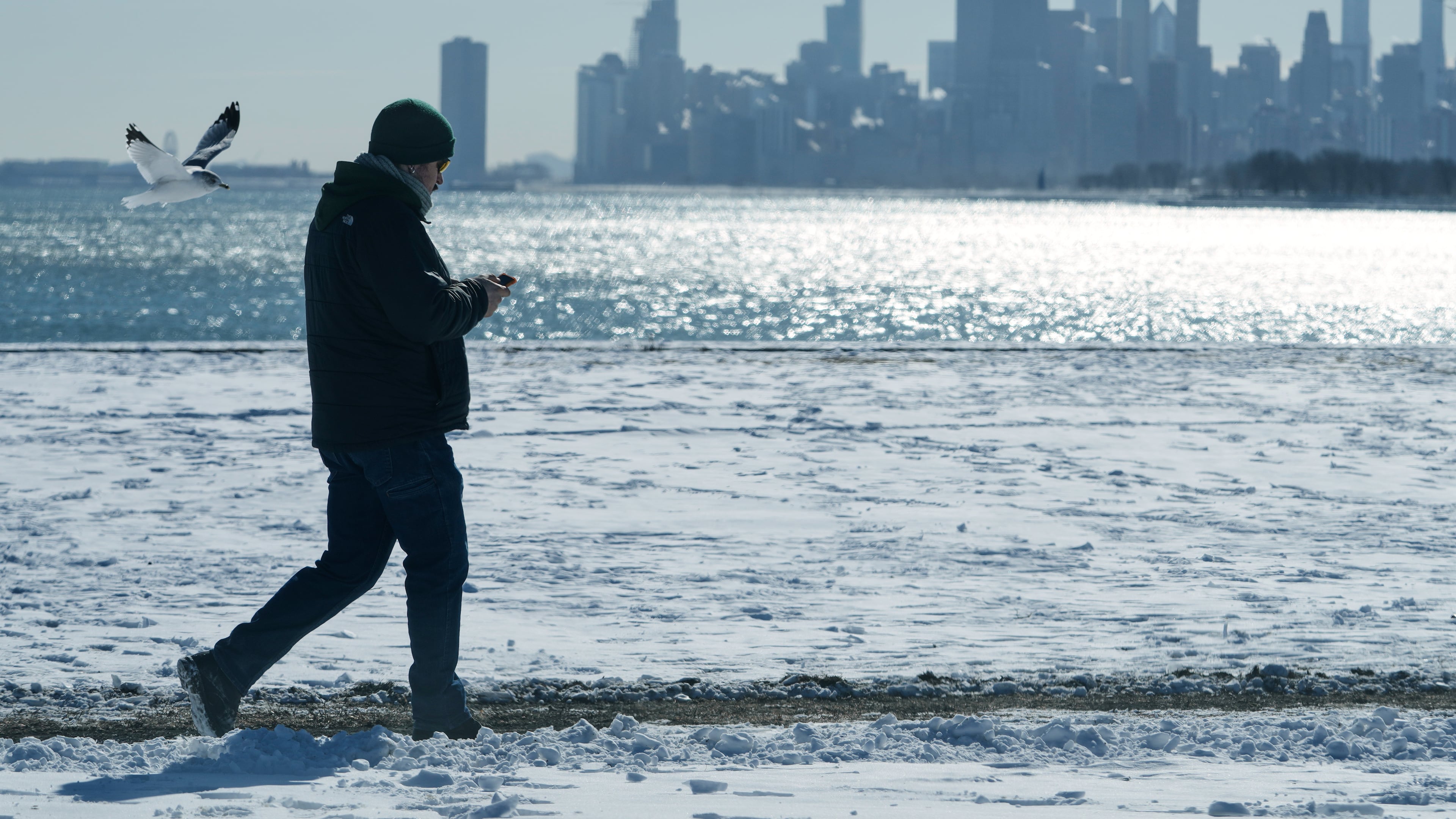 FILE - A person walks near the snow-covered sand at Lake Michigan in Chicago, Jan. 28, 2026. (AP Photo/Nam Y. Huh, File)