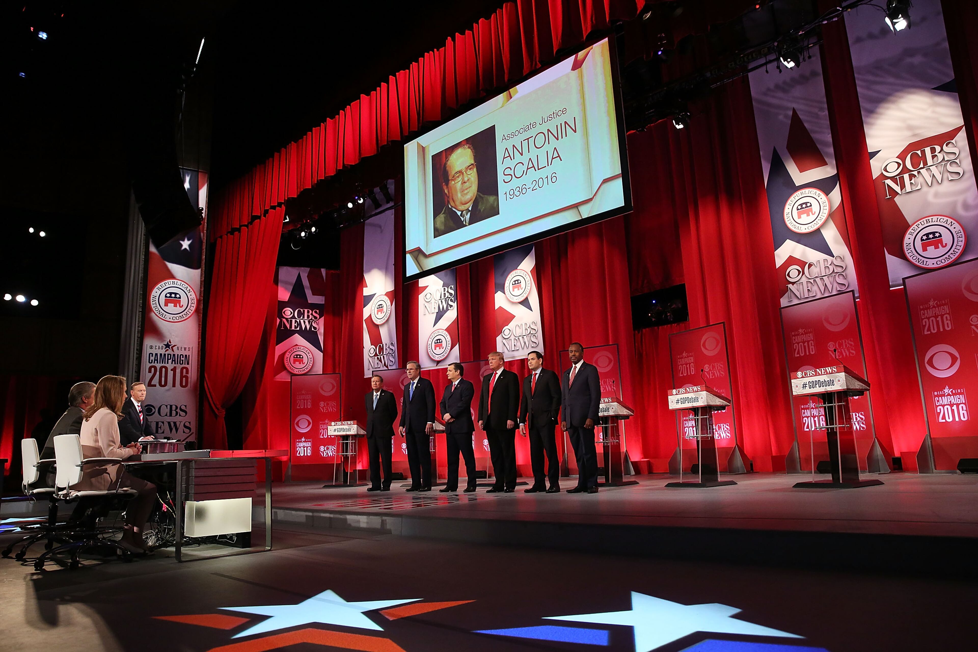 Republican presidential candidates (L-R) Ohio Governor John Kasich, Jeb Bush, Sen. Ted Cruz (R-TX), Donald Trump, Sen. Marco Rubio (R-FL) and Ben Carson stand on stage as a picture of U.S. Supreme Court Justice Antonin Scalia, who has passed away today, is seen during a CBS News GOP Debate February 13, 2016 at the Peace Center in Greenville, South Carolina. Residents of South Carolina will vote for the Republican candidate at the primary on February 20. (Photo by Spencer Platt/Getty Images)