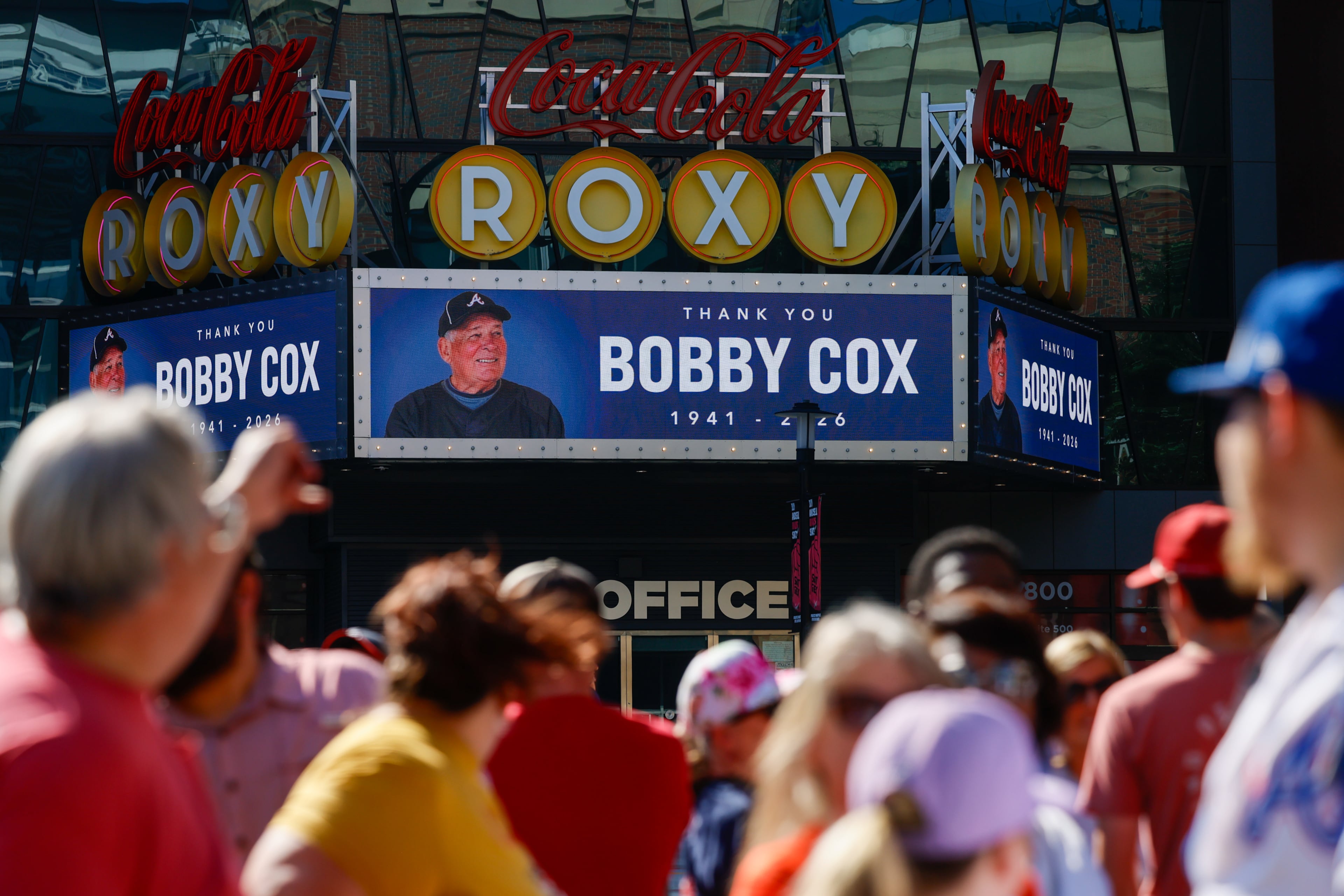 Fans wait to get into the stadium as a tribute to late legendary Braves manager Bobby Cox appears on the Roxy marquee in Truist Park in Atlanta on Tuesday, May 12, 2026. (Arvin Temkar/AJC)