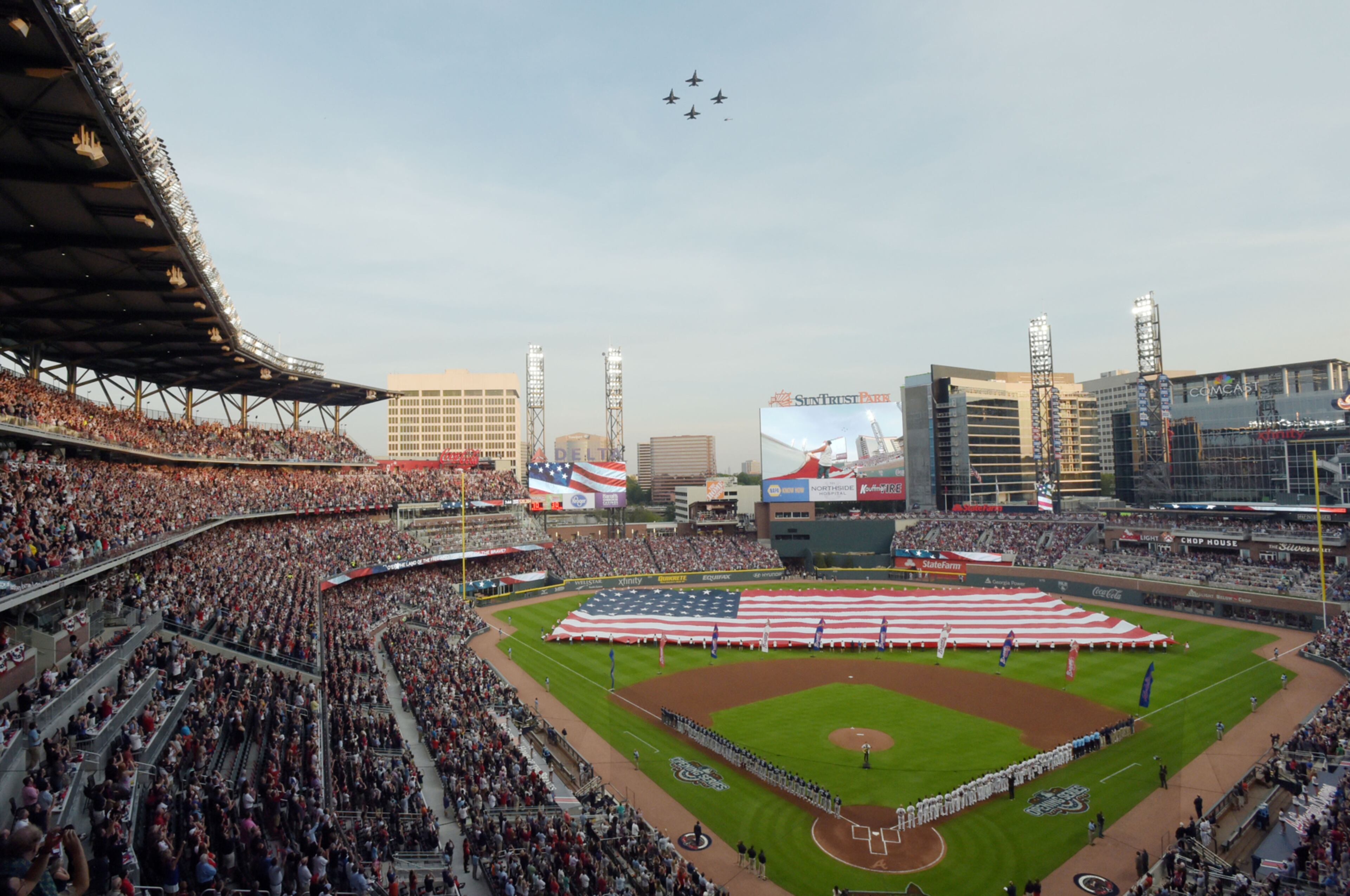 April 14, 2017 ATLANTA Braves staff holds the American flag on the field, United States Navy F/A-18A+ Hornets from VFC-12 out of Oceana, Va., perform a flyover at the concluasion of the national anthem before the Atlanta Braves play the San Diego Padres in the season opener in the new SunTrust Park Friday, April 14, 2017. KENT D. JOHNSON / AJC