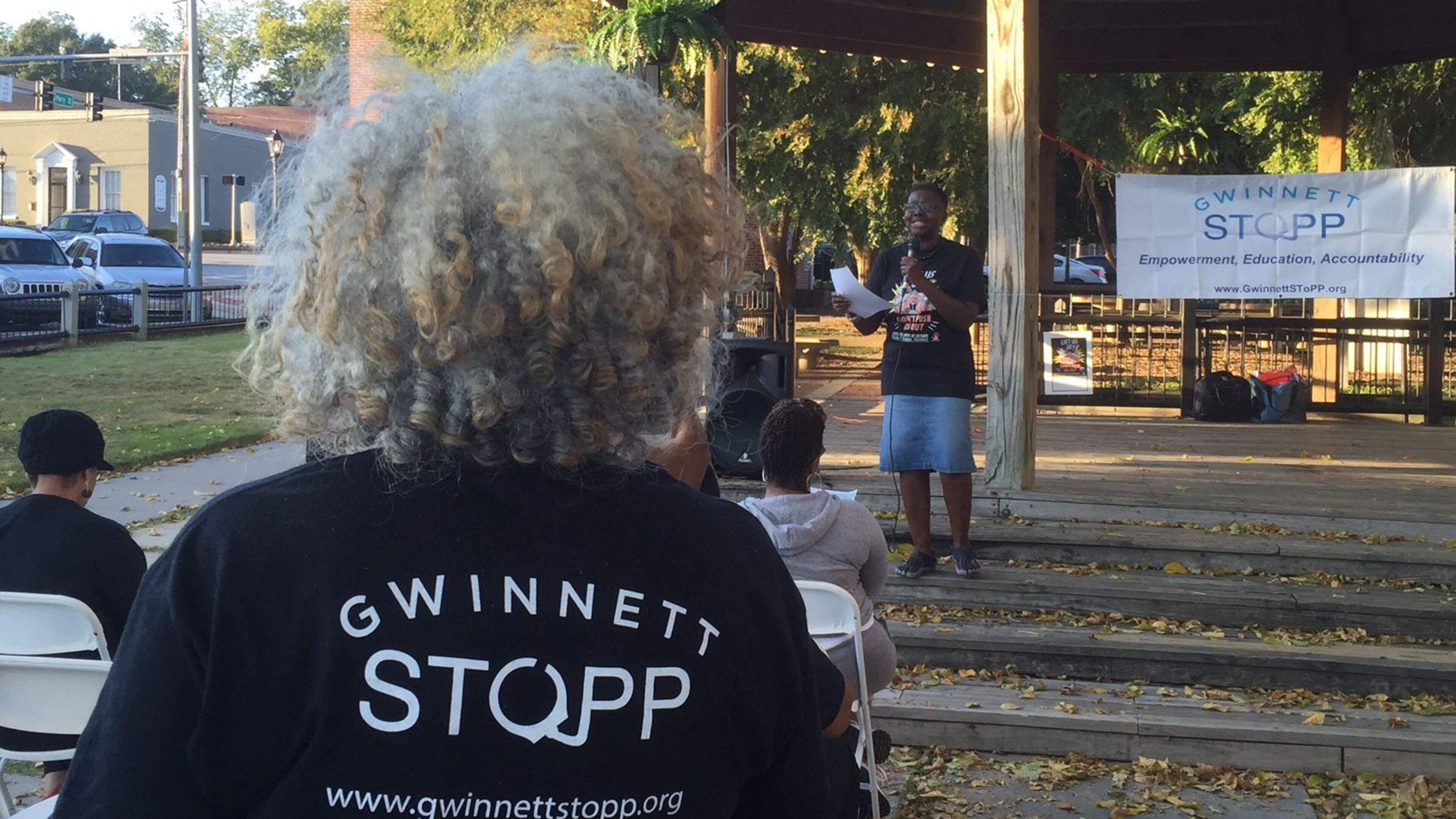 Gwinnett SToPP advisory board member Marlyn Tillman, in the black T-shirt, listens as fellow member Penny Poole speaks at the group’s rally Monday afternoon. ERIC STIRGUS/STAFF