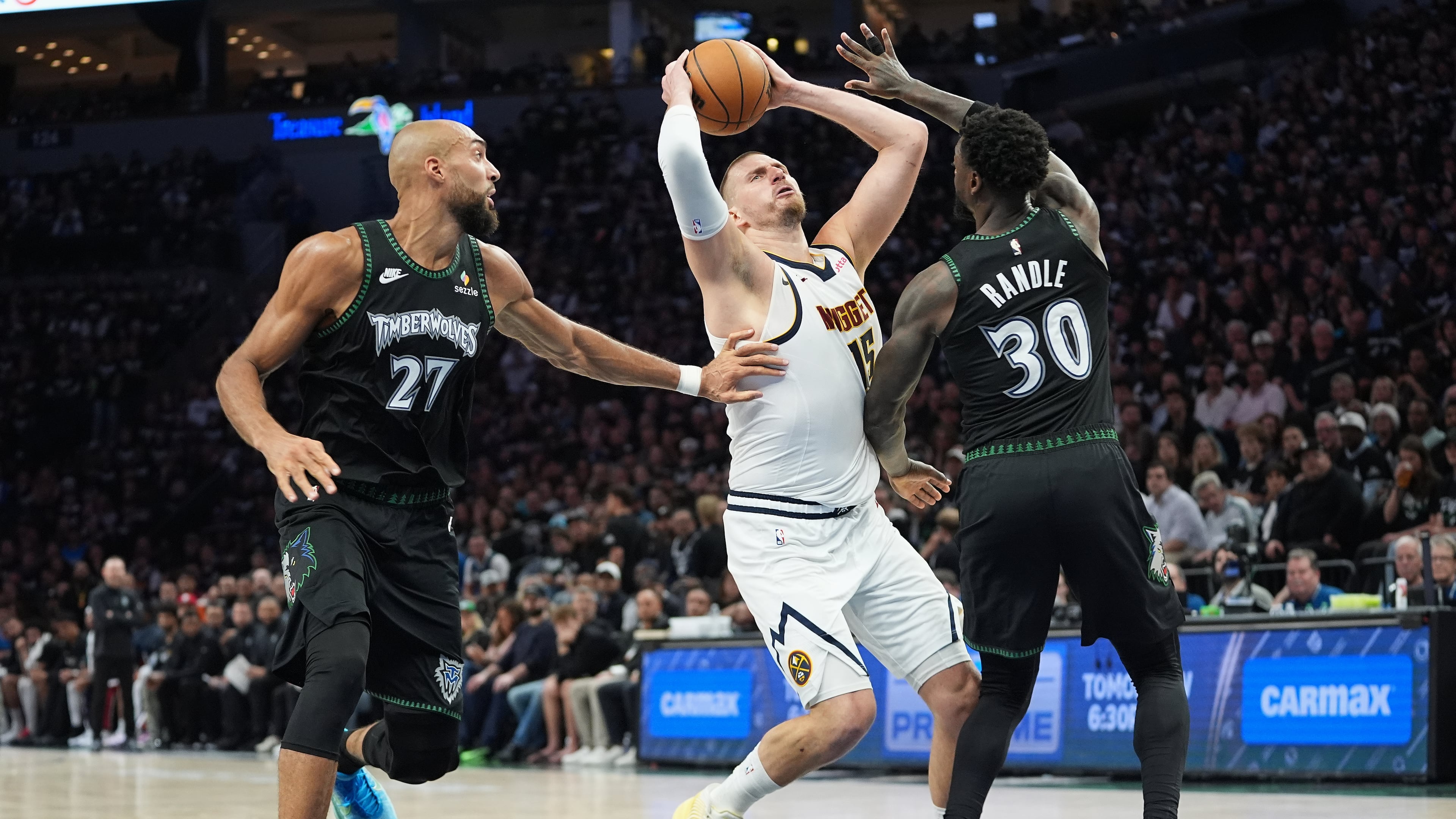 Denver Nuggets center Nikola Jokic (15) works toward the basket as Minnesota Timberwolves center Rudy Gobert (27) and forward Julius Randle (30) defend during the first half in Game 3 of a first-round NBA basketball playoff series, Thursday, April 23, 2026, in Minneapolis. (AP Photo/Abbie Parr)
