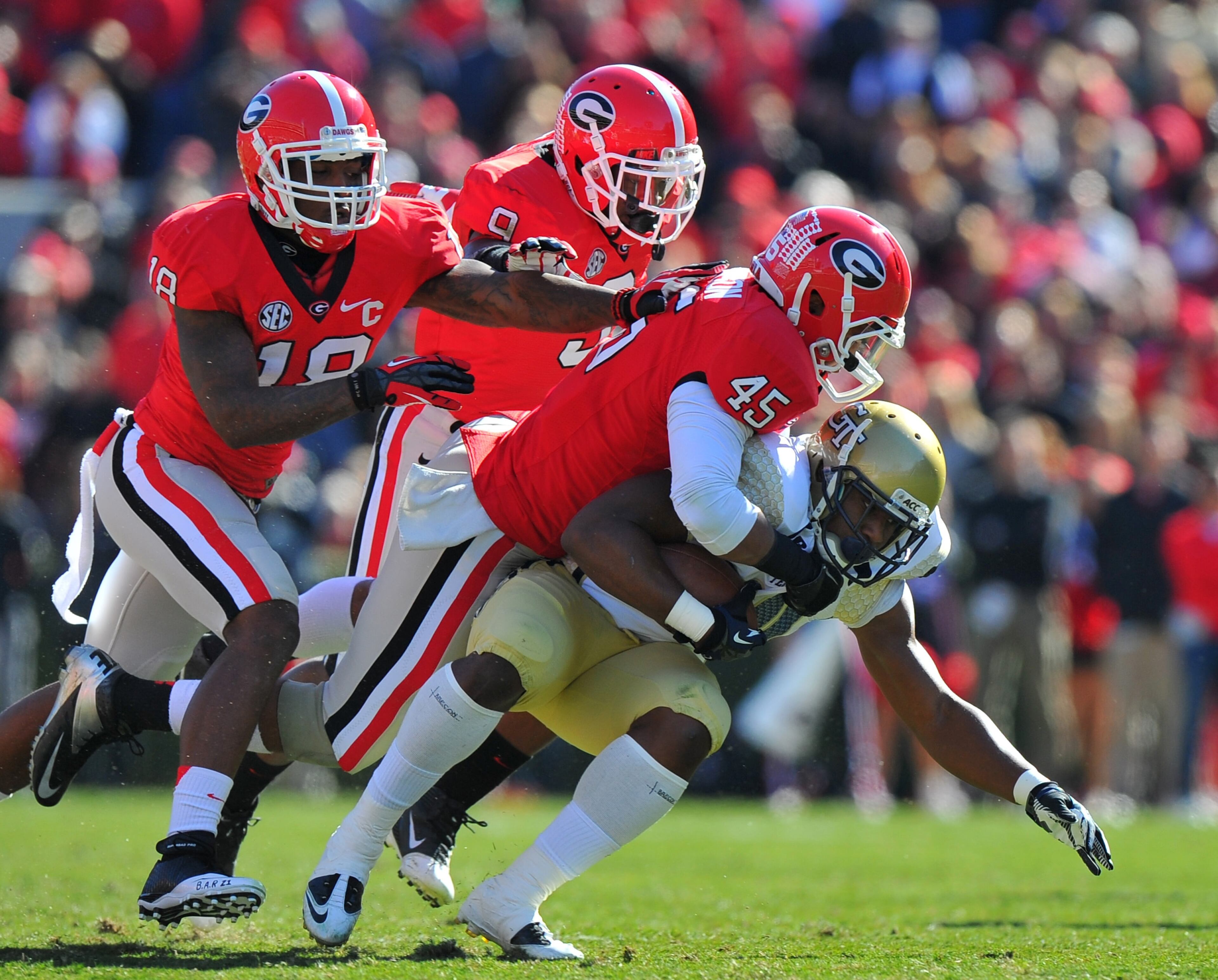Georgia Tech's David Sims (20) is stopped by Georgia's Christian Robinson (45), Bacarri Rambo (18) and Curtis Wyatt in the first quarter.