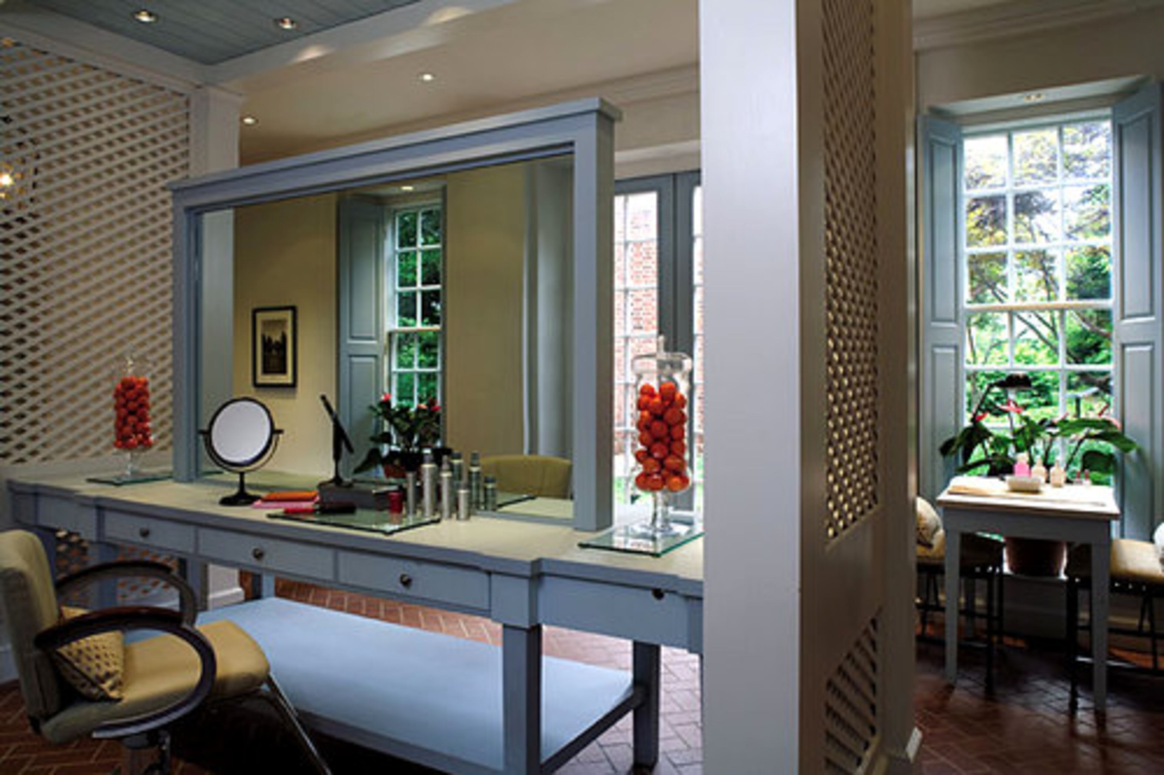 The conservatory salon carries out the garden feel with its brick floor, handcrafted cabinetry painted Yarmouth blue and large windows overlooking the gardens.