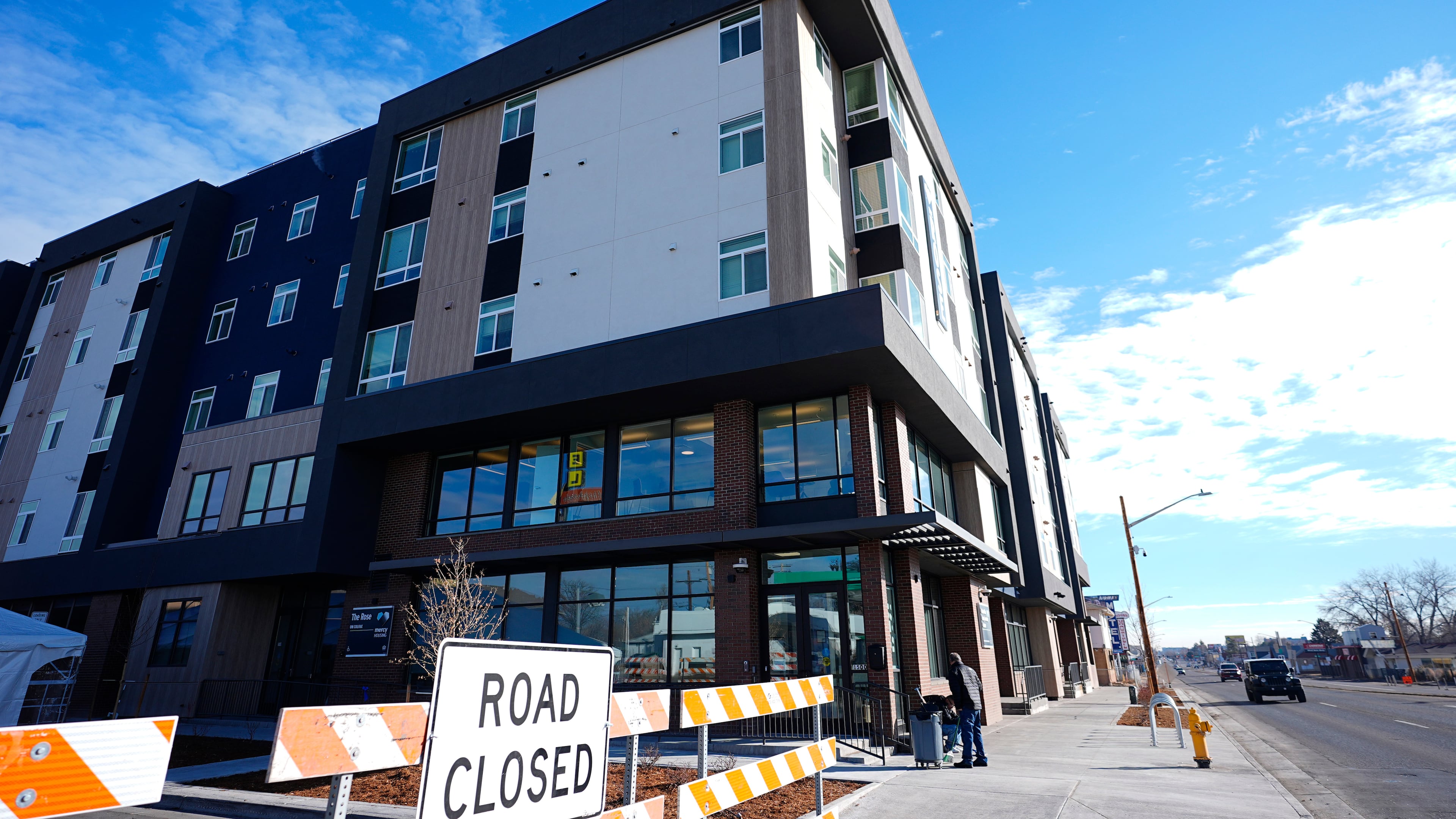 FILE - A person sweeps outside during the grand opening of the Rose on Colfax, a new affordable housing community with a co-located childcare center in the East Colfax neighborhood, Jan. 24, 2024, in Denver. (AP Photo/David Zalubowski, File)