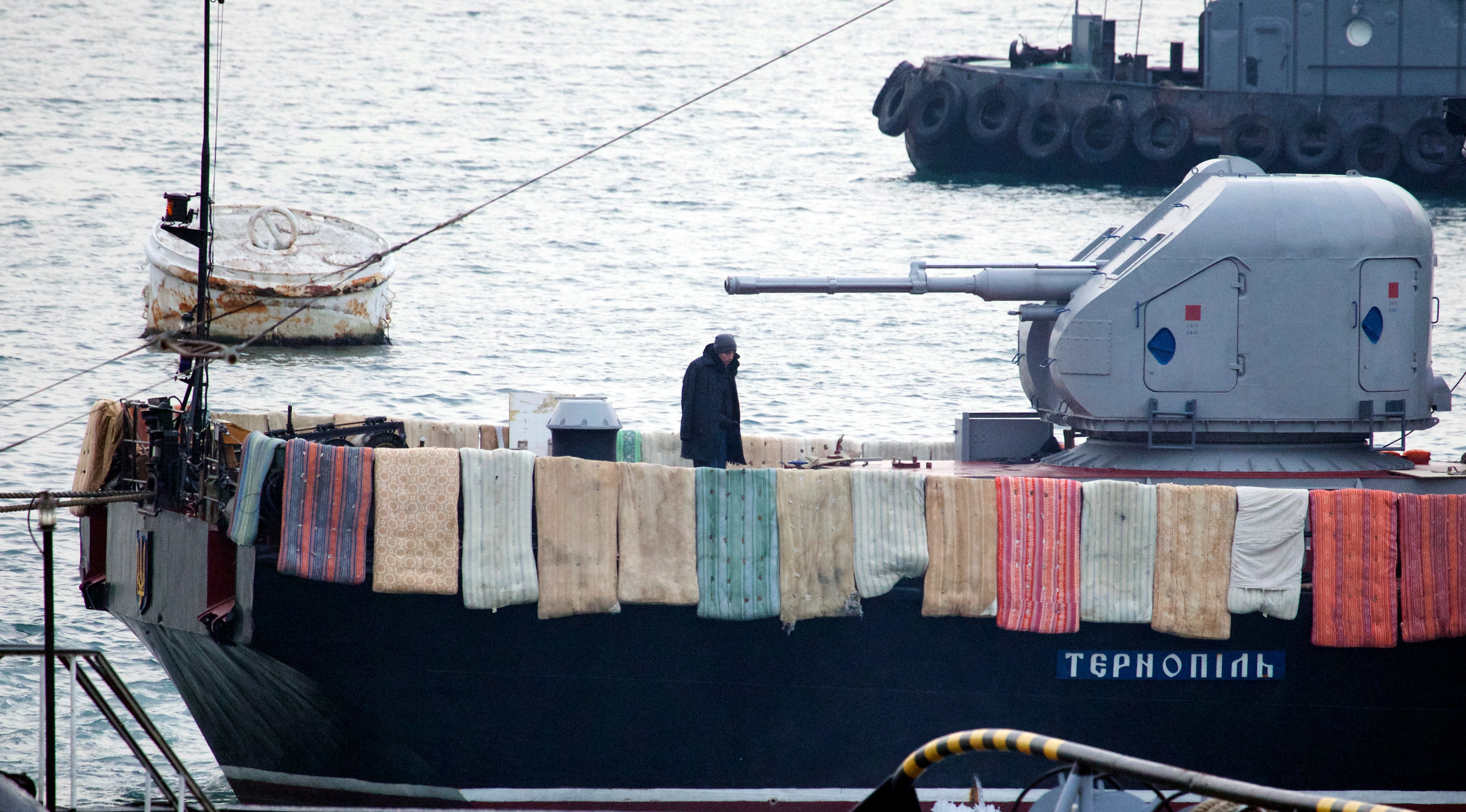 A Ukrainian sailor warms himself as he stands watch looking for Russian soldiers who may attempt to take over his vessel Ternopil, in Sevastopol, Ukraine, on Tuesday, March 4, 2014. The blankets and mattresses are placed over the side of the ship to hinder any attempted assault. (AP Photo/Ivan Sekretarev)