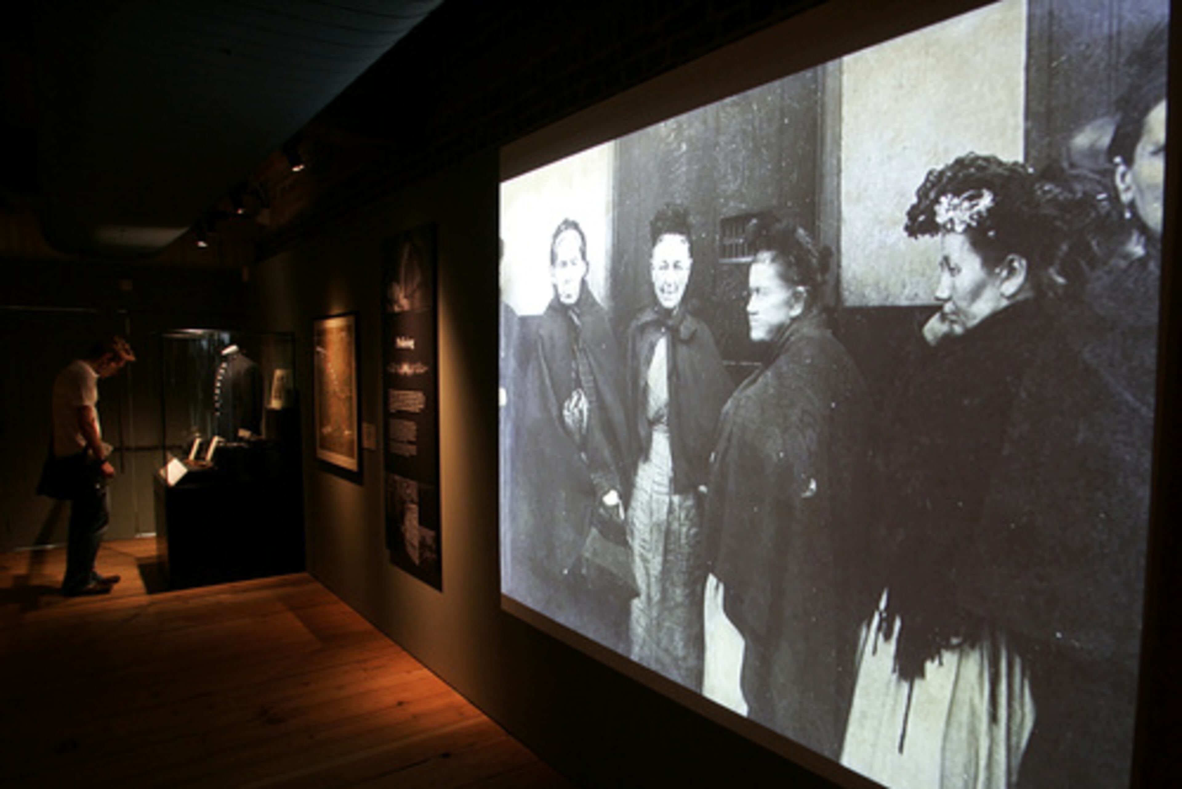 An old photograph of London's East End is seen on a screen as a man looks at another display. The museum's exhibition, which continues through Nov. 2, places the killings in the context of the extreme poverty of the victims and so many others living in the teeming East End of London.