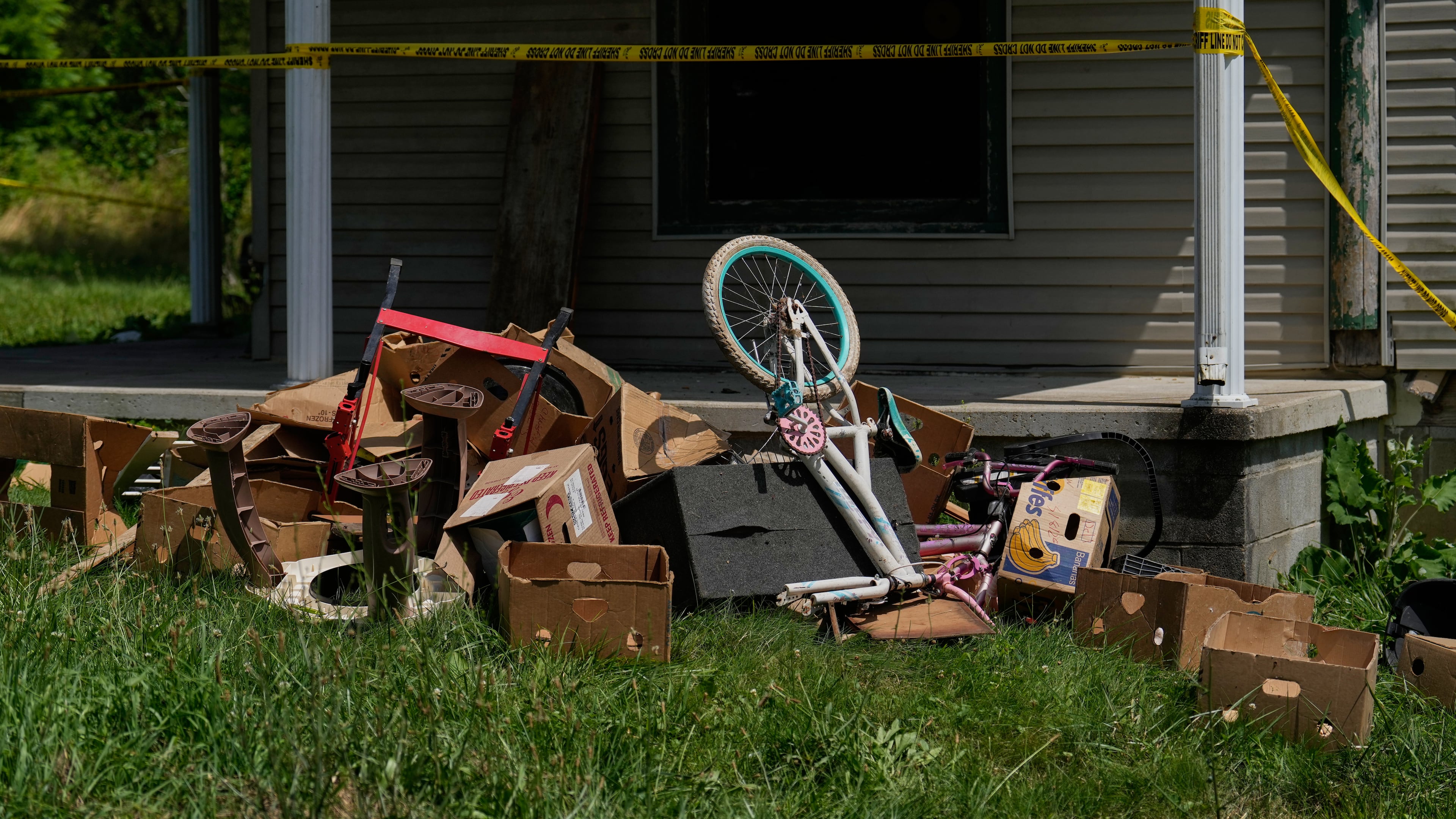 Police tape and debris are seen at a home where authorities say they removed 16 children and arrested four adults in Hamden, Ohio, Wednesday, July 1, 2026. (AP Photo/Carolyn Kaster)