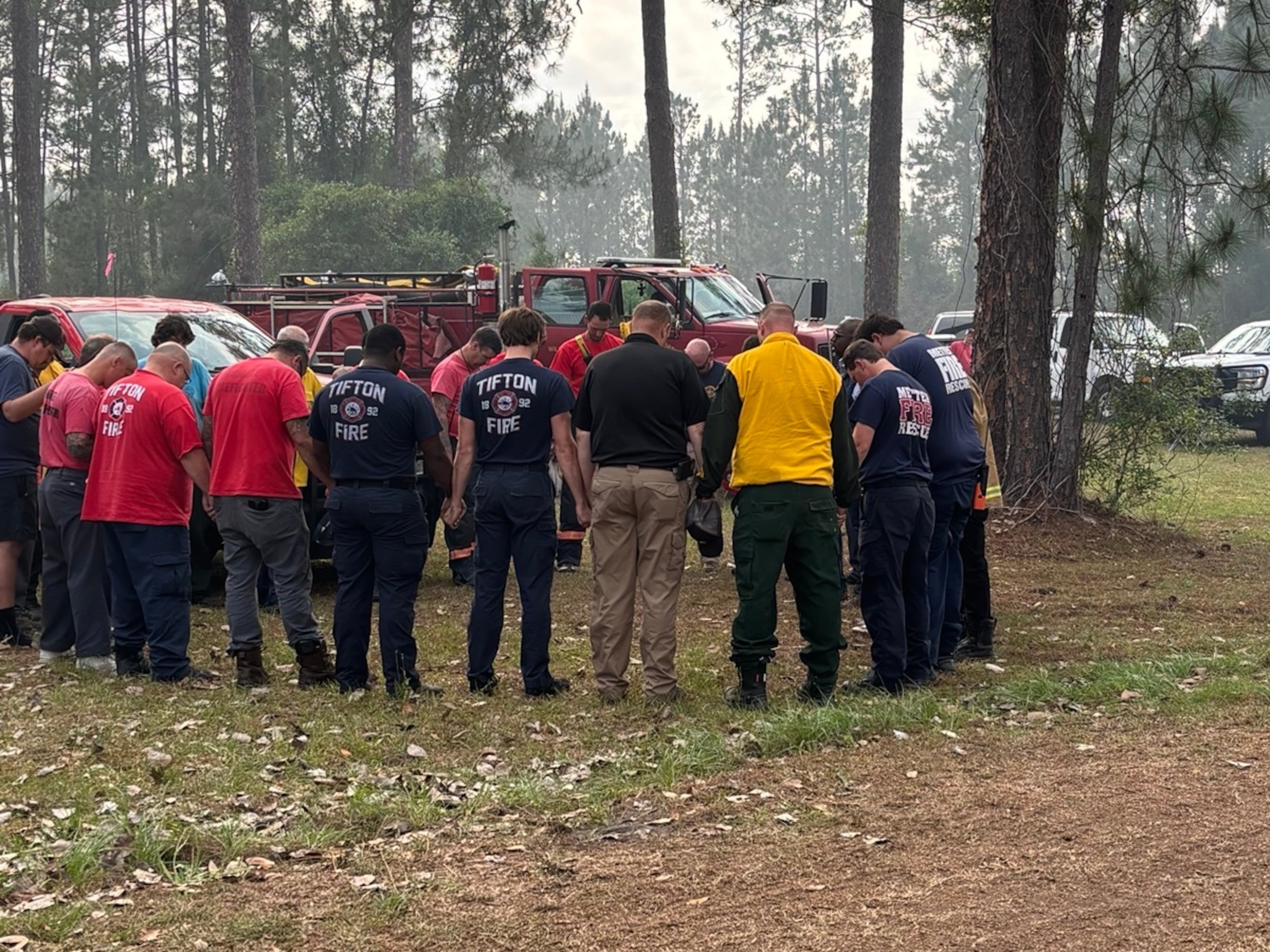 U.S. Sen. Raphael Warnock prays with first responders as he visits Brantley County to survey damage from wildfires on Monday. (Courtesy of the office of U.S. Sen. Raphael Warnock)