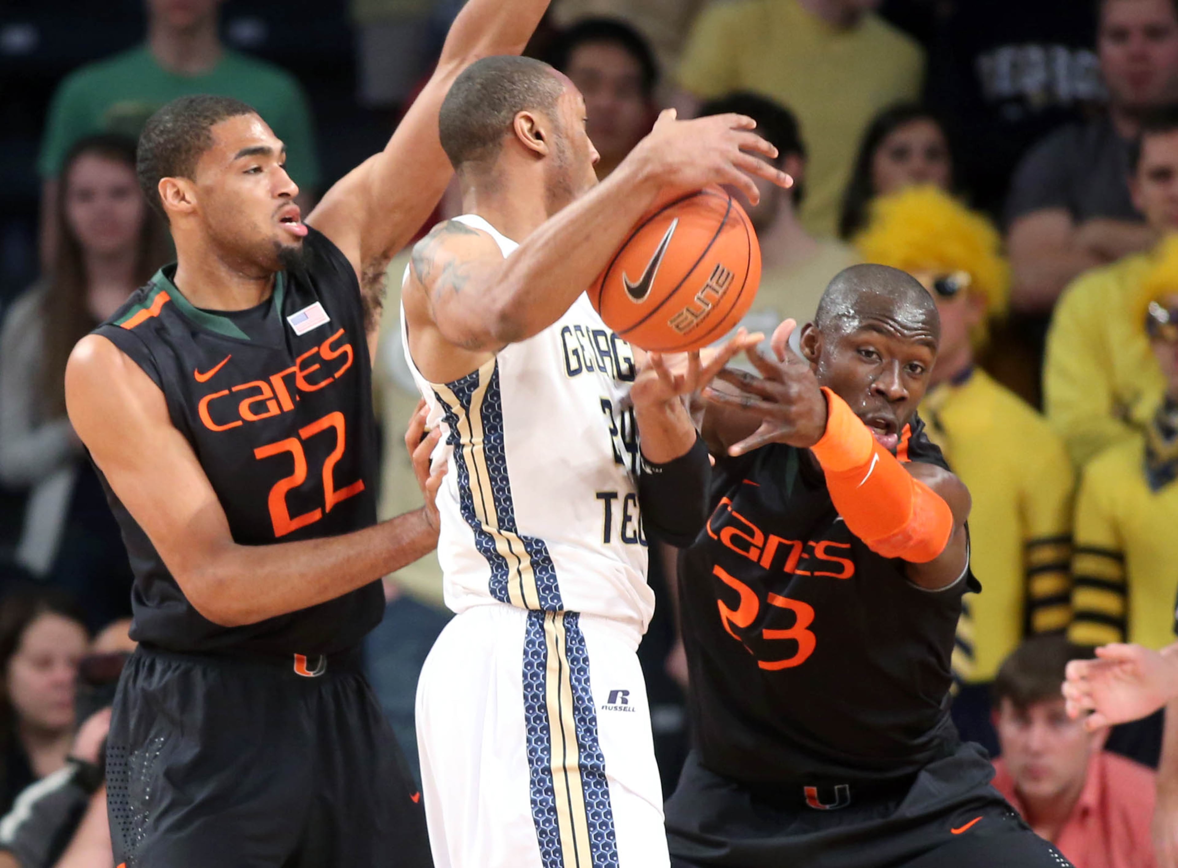 Georgia Tech forward Kammeon Holsey, center, gets defended by Miami forward Donnavan Kirk (22) and center Tonye Jekiri, right, first half of an NCAA college basketball game, Saturday, Jan. 18, 2014, in Atlanta. Miami defeated Georgia Tech 56-42.