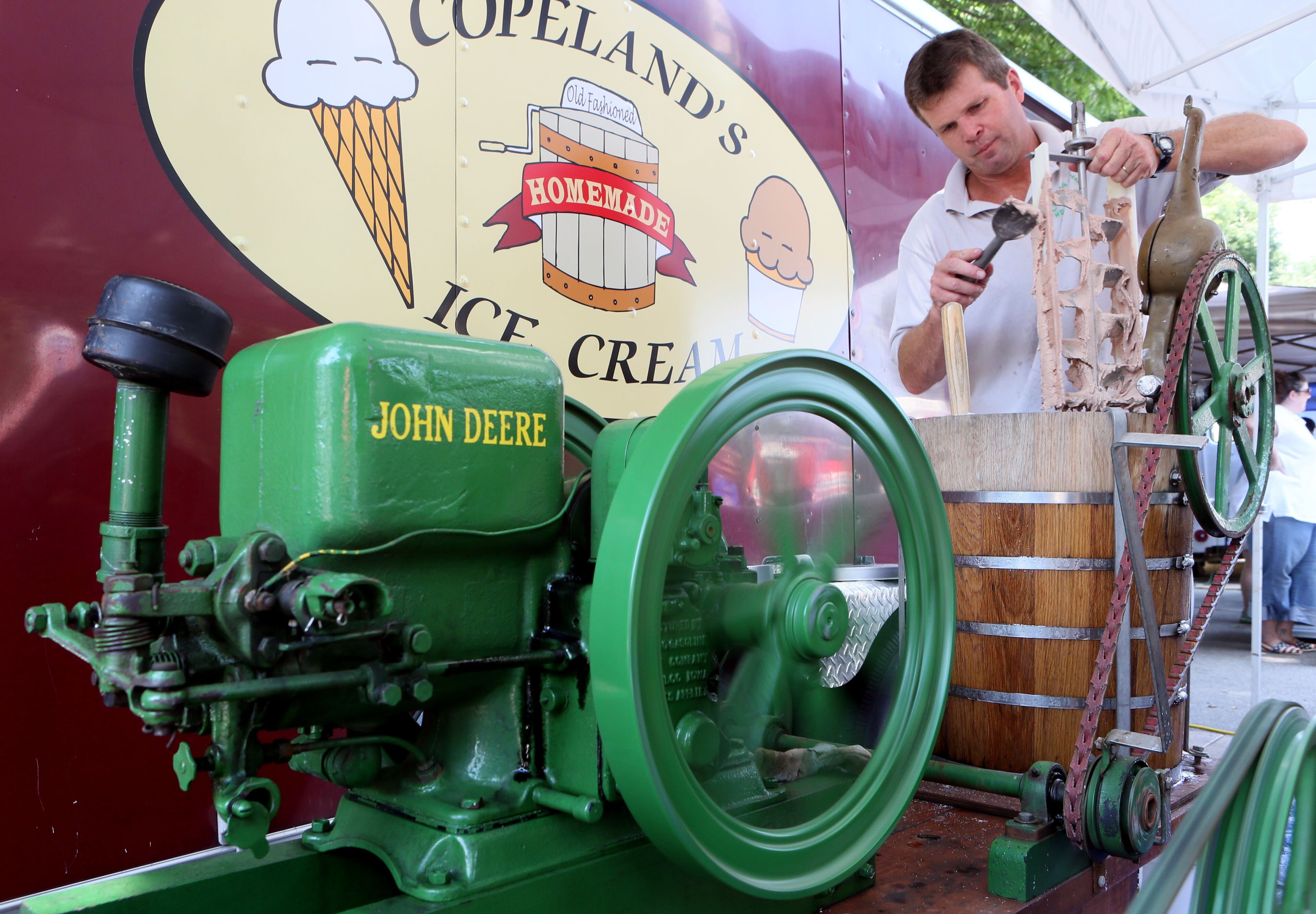 Robert Copeland scraped chocolate ice cream off a churn driven by a 1925 John Deere "Hit & Miss" engine as local artisans and national classics presented their best products at the 4th Annual Atlanta Ice Cream Festival at Piedmont Park in Atlanta on Saturday, July 26, 2014. There was a variety of health /wellness agencies, fitness routines, vendors, entertainment, bands and fun family activities. (Photo by Phil Skinner)