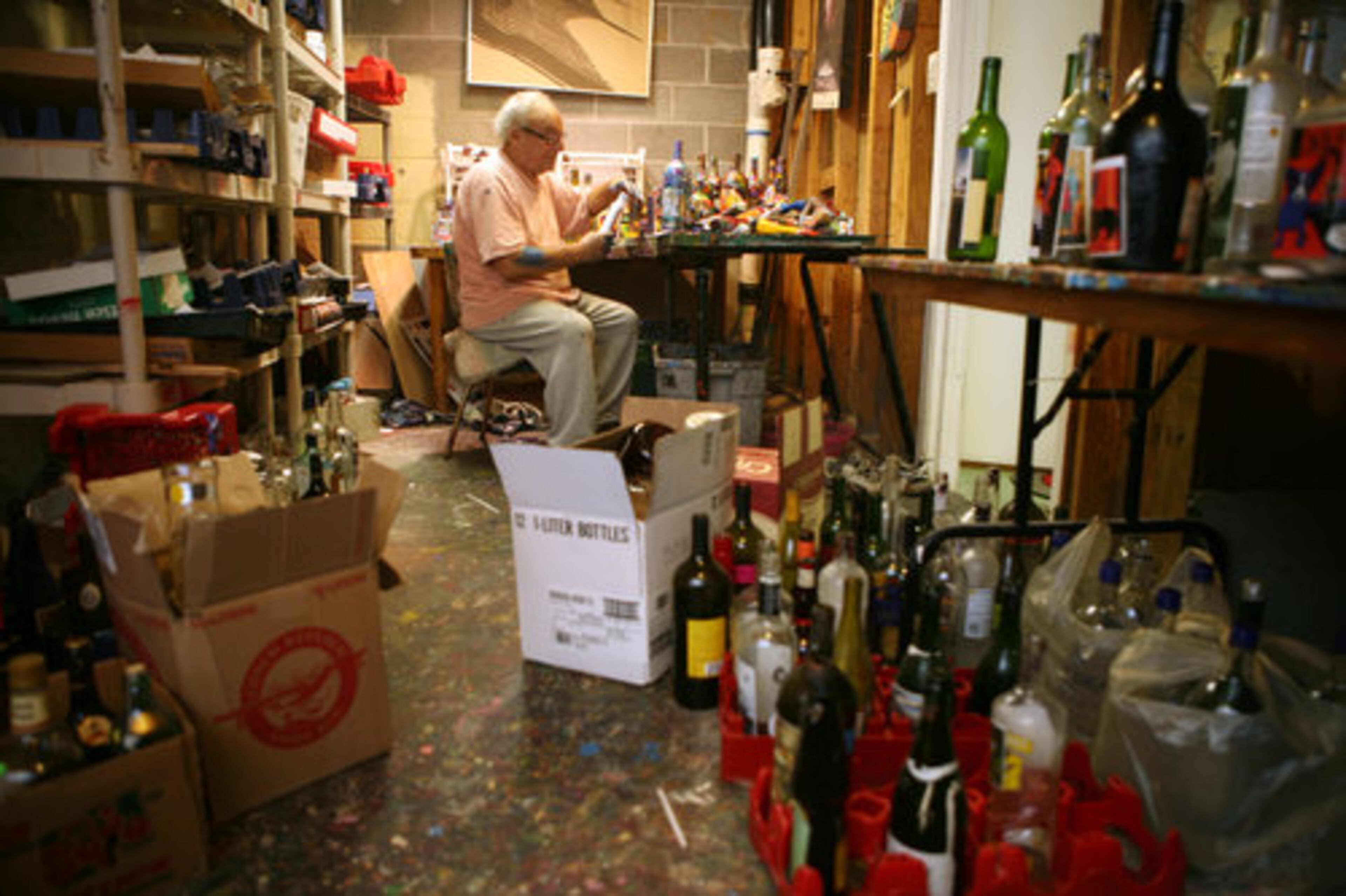 King works in his studio surrounded by unpainted bottles.