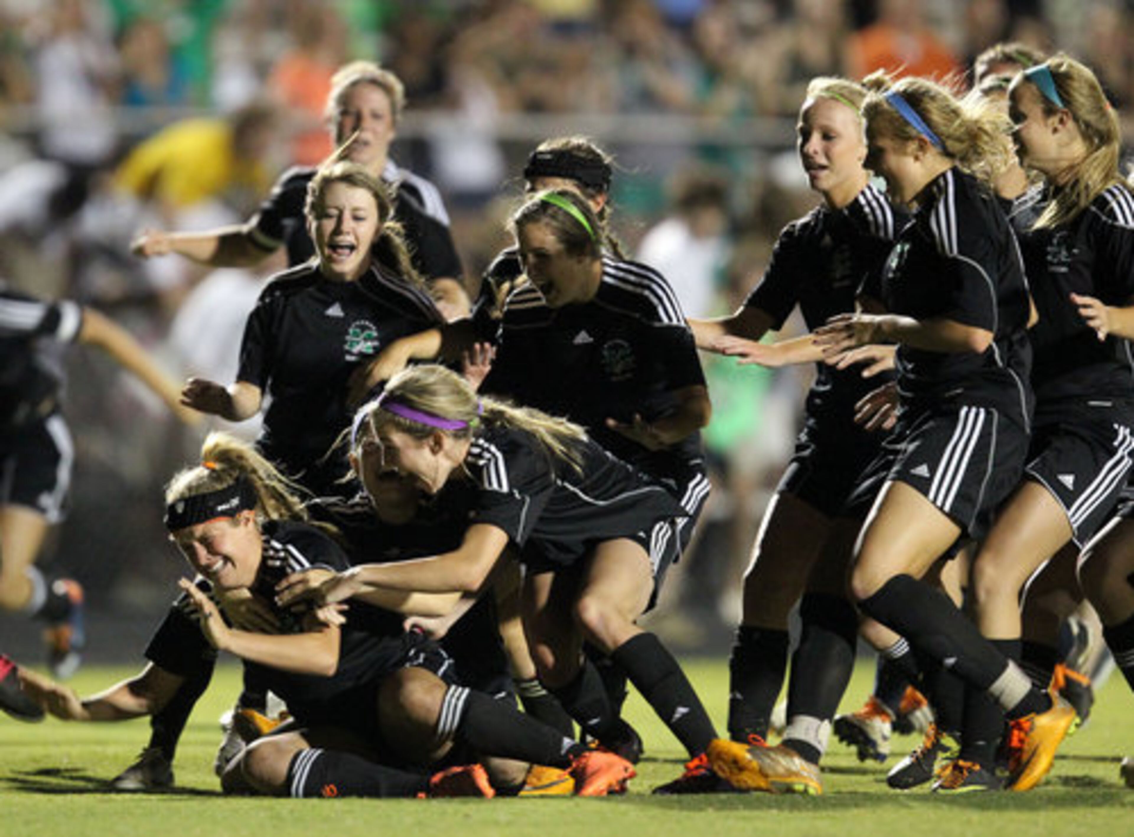 McIntosh players rush to celebrate with Amanda Bartholomew (21, lower left) after Bartholomew made the game-winning penalty kick in the Class AAAA girls soccer state championship game at Whitewater High School Saturday afternoon in Fayetteville, Ga., May 19, 2012. McIntosh defeated Whitewater 2-1 in penalty kicks.