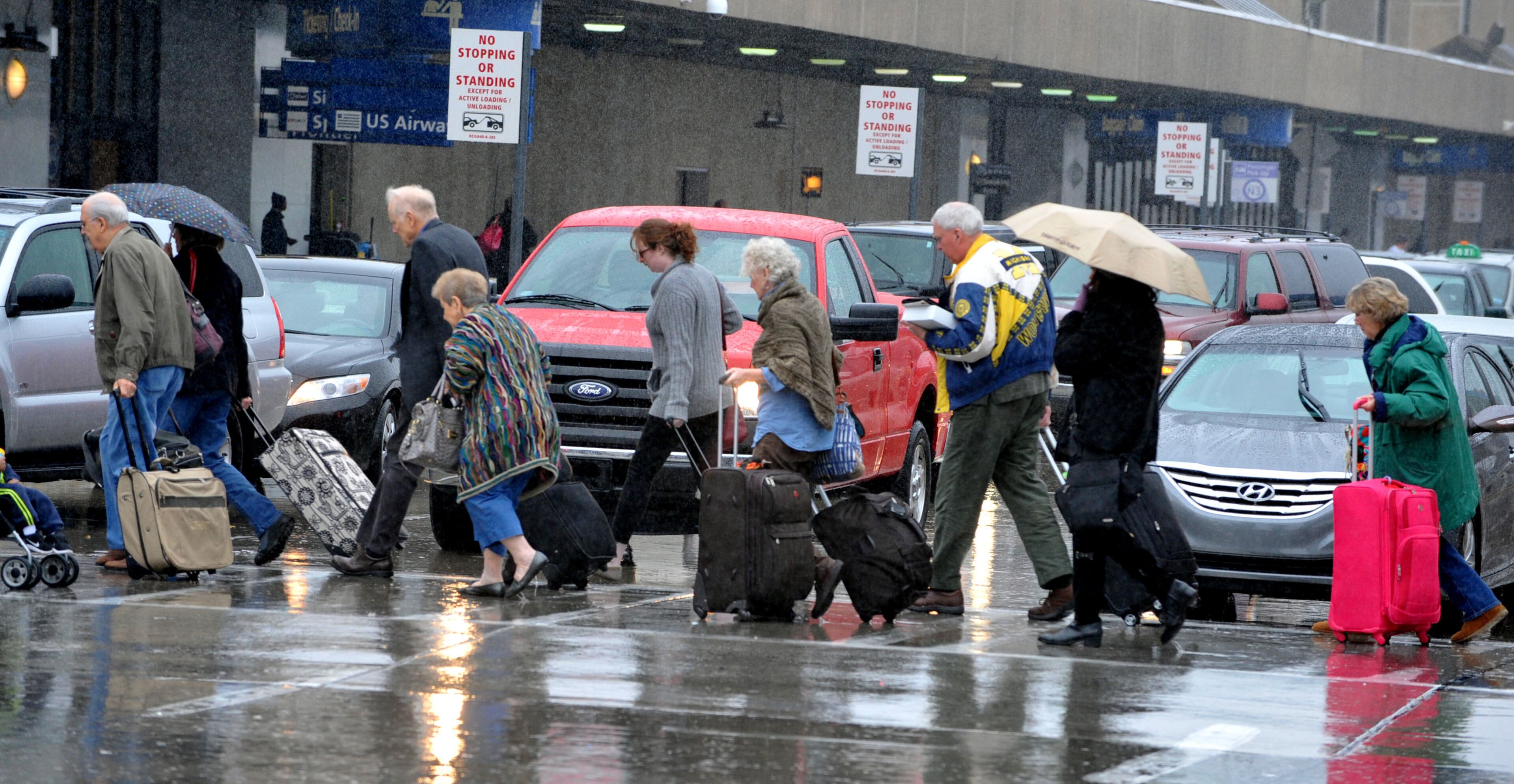 Travelers make their way into Hartsfield Jackson International Airport to flights Tuesday, November 26, 2013. A steady rain, which is predicted to worsen later in the day, was not causing flight delays at mid-day. KENT D. JOHNSON / KDJOHNSON@AJC.COM