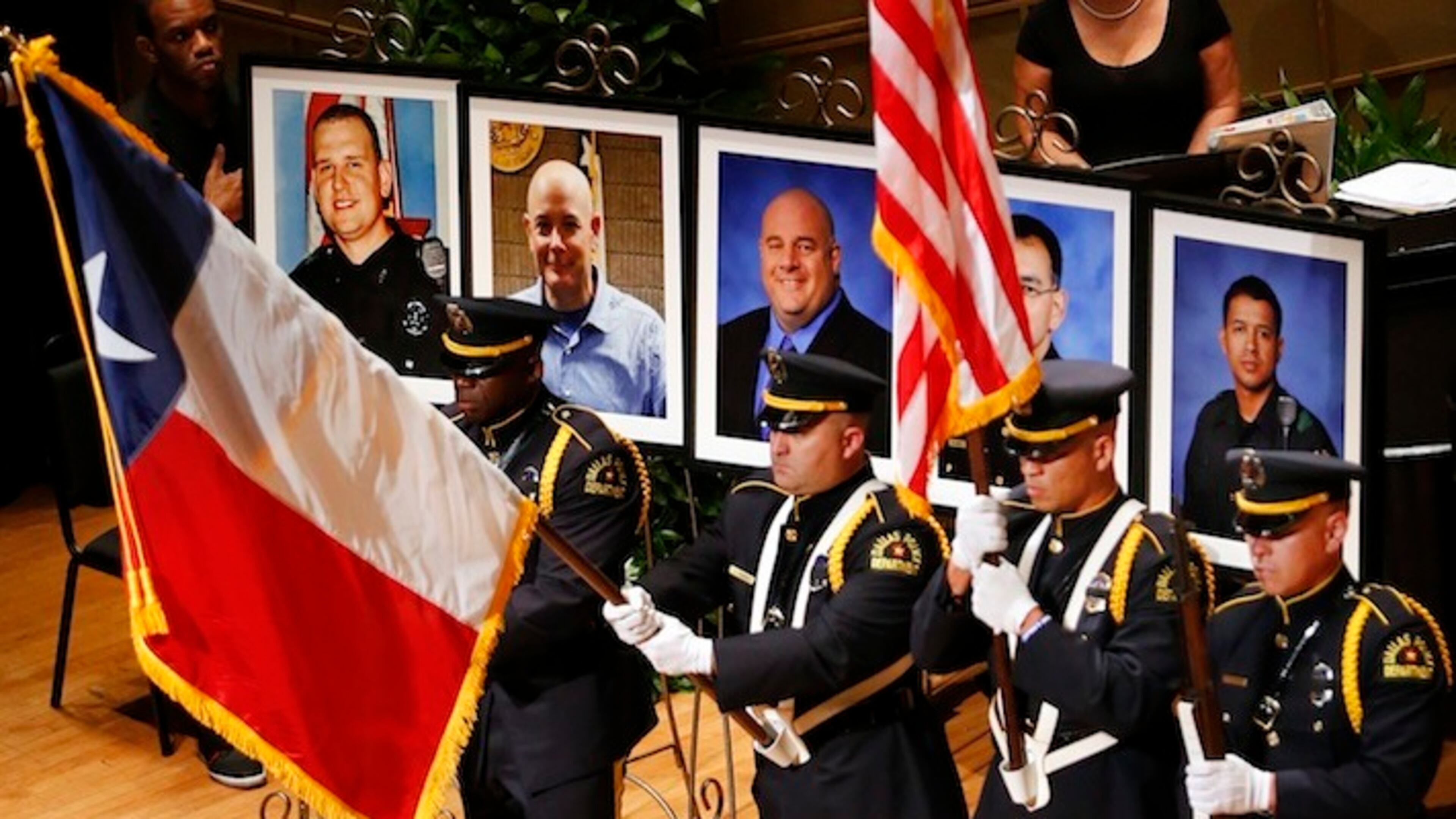 The Dallas Police color guard presents the colors before the photos of five fallen officers being remembered during an interfaith memorial service at the Morton H. Meyerson Symphony Center in Dallas, Tuesday, July 12, 2016. Four Dallas police officers and one Dallas Area Rapid Transit (DART) officer were gunned down last week in downtown Dallas at a protest rally. The victims are depicted, from left, Dallas PD officer Michael Krol, DART officer Brent Thompson, Dallas police Sr. Cpl. Lorne Ahrens, Dallas police Sgt. Michael Smith, and Dallas police Officer Patrick Zamarripa. (Tom Fox/The Dallas Morning News via AP)