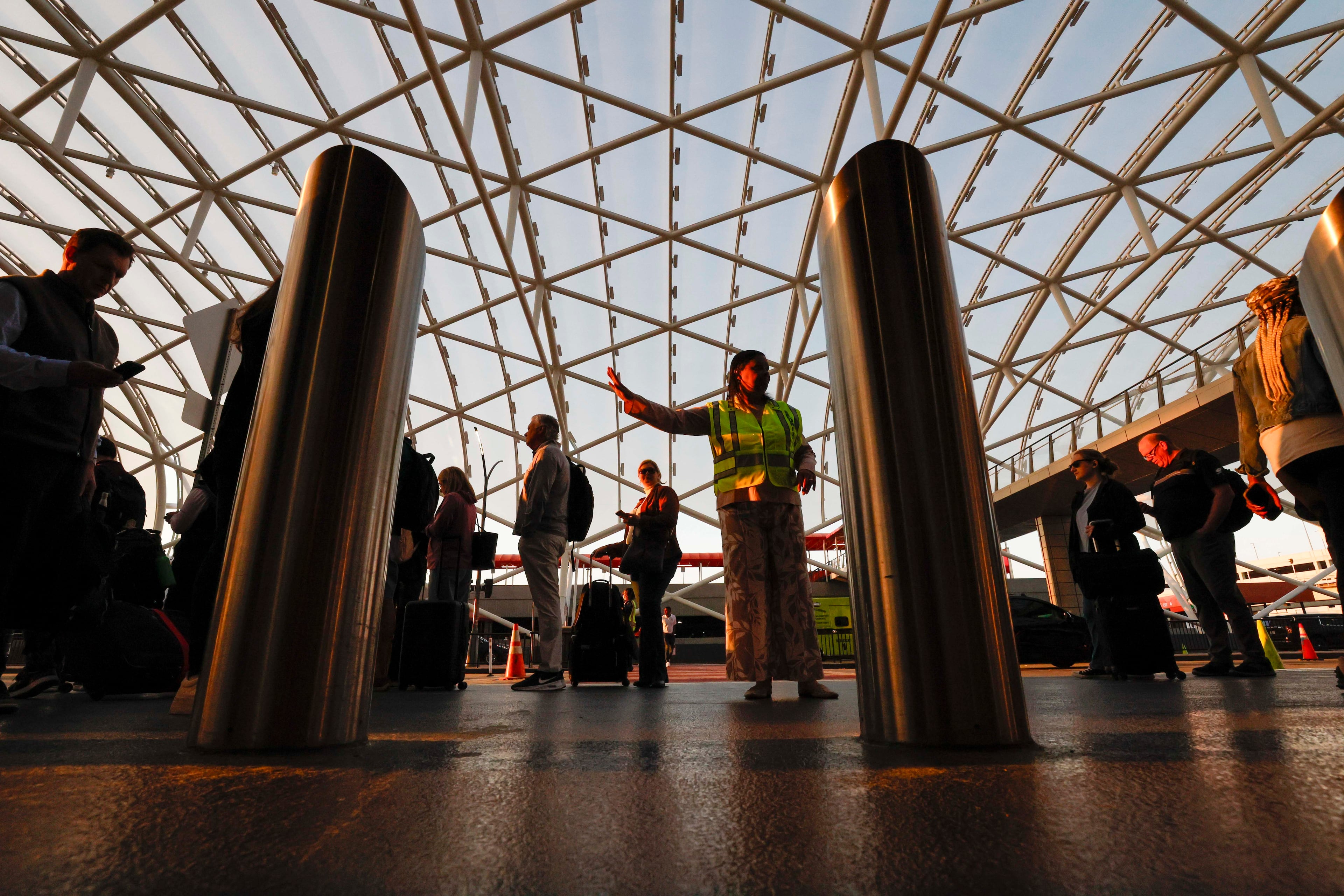 An airport agent assists travelers on the sidewalks for TSA security checks early Monday morning at Hartsfield-Jackson Atlanta International Airport during the partial government shutdown on March 23, 2026. (Miguel Martinez/AJC)