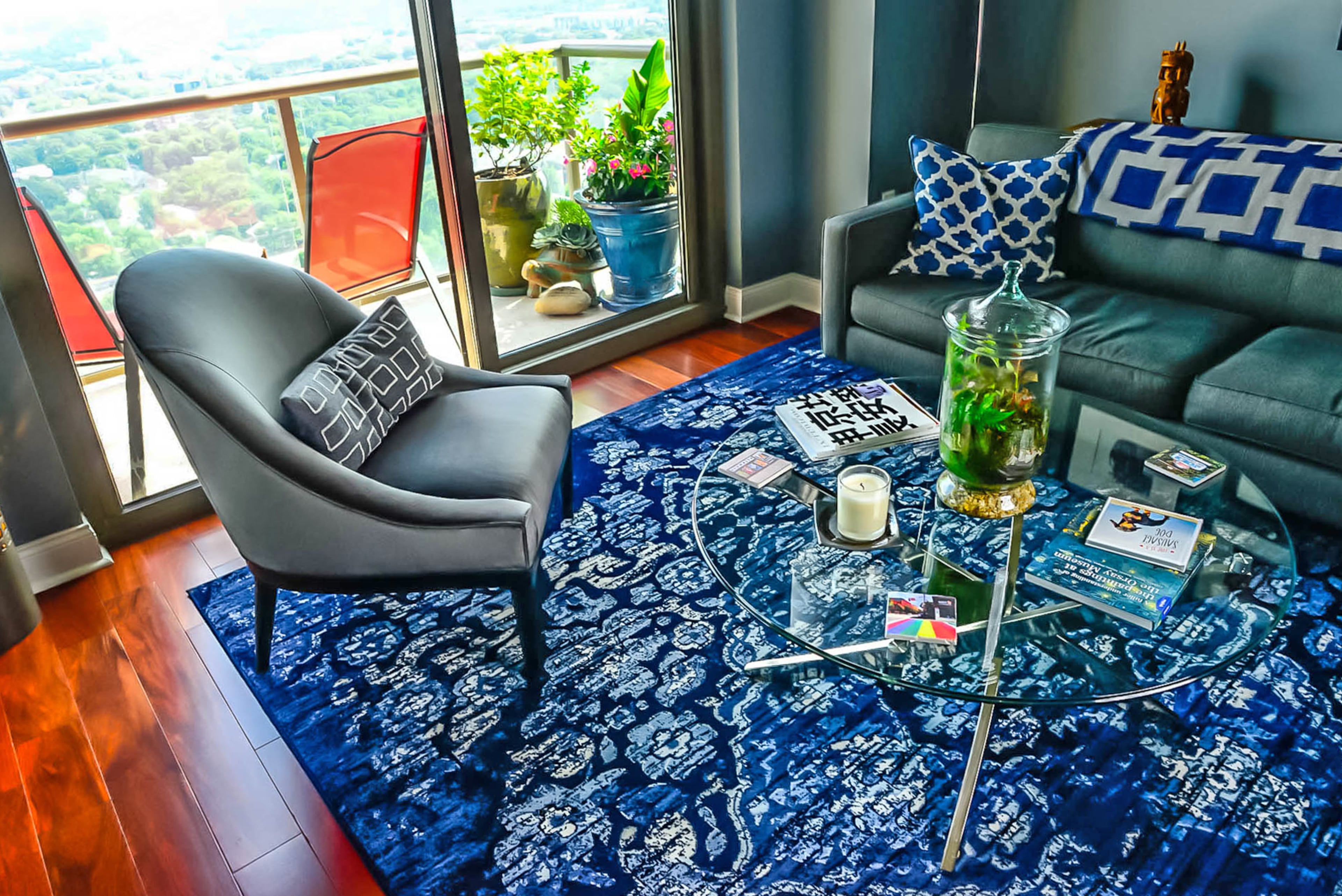 Gray velvet accent chairs from Mitchell Gold + Bob Williams and a round glass-top coffee table with a metal base are among the condo's modern interiors. The balcony, which has room for a small container garden, is one of two in the high-rise unit at The Atlantic in Midtown.