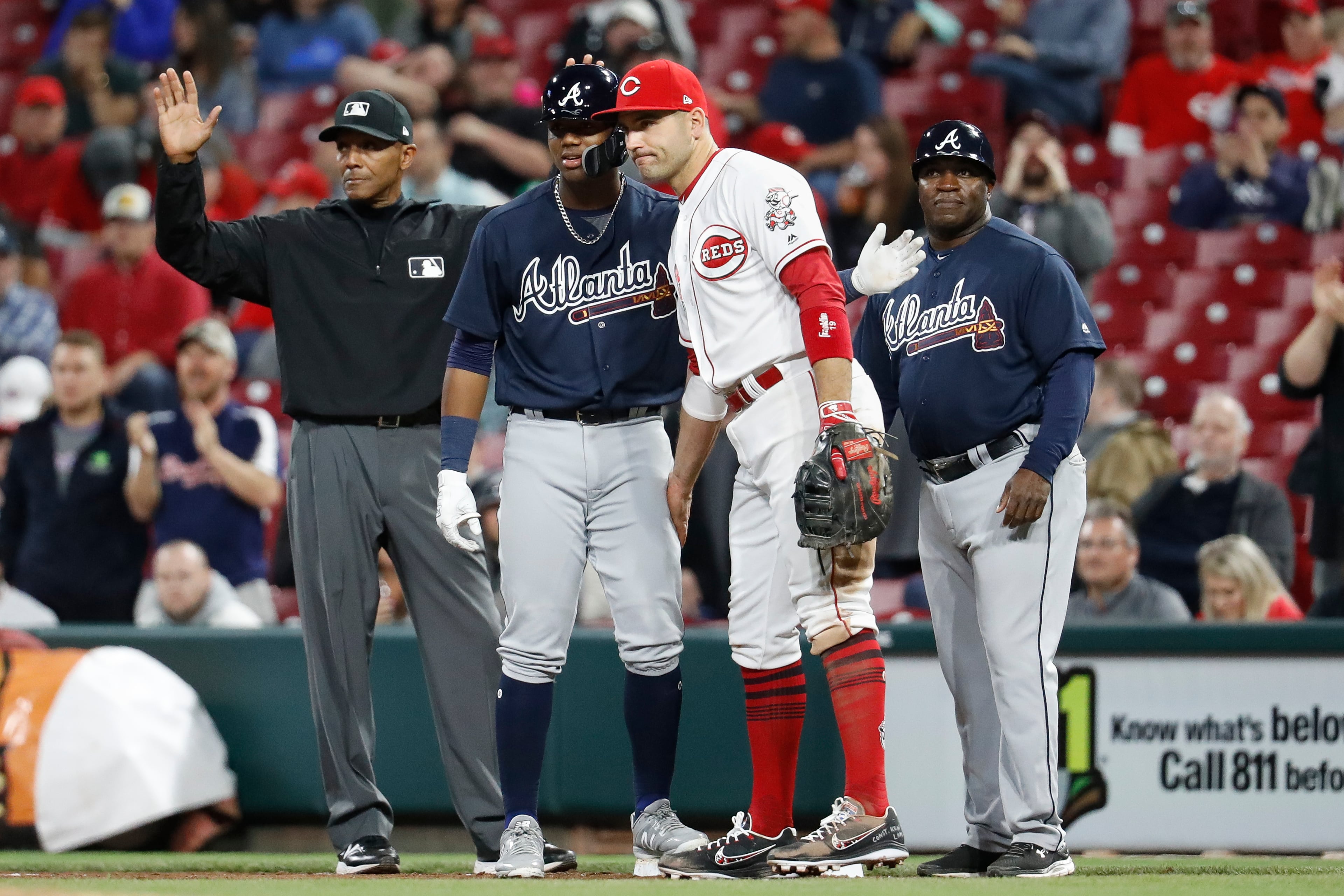 Atlanta Braves' Ronald Acuna Jr., center left, is congratulated by Cincinnati Reds first baseman Joey Votto, center right, after Acuna recorded his first hit in the majors, during the eighth inning of a baseball game Wednesday, April 25, 2018, in Cincinnati. (AP Photo/John Minchillo)