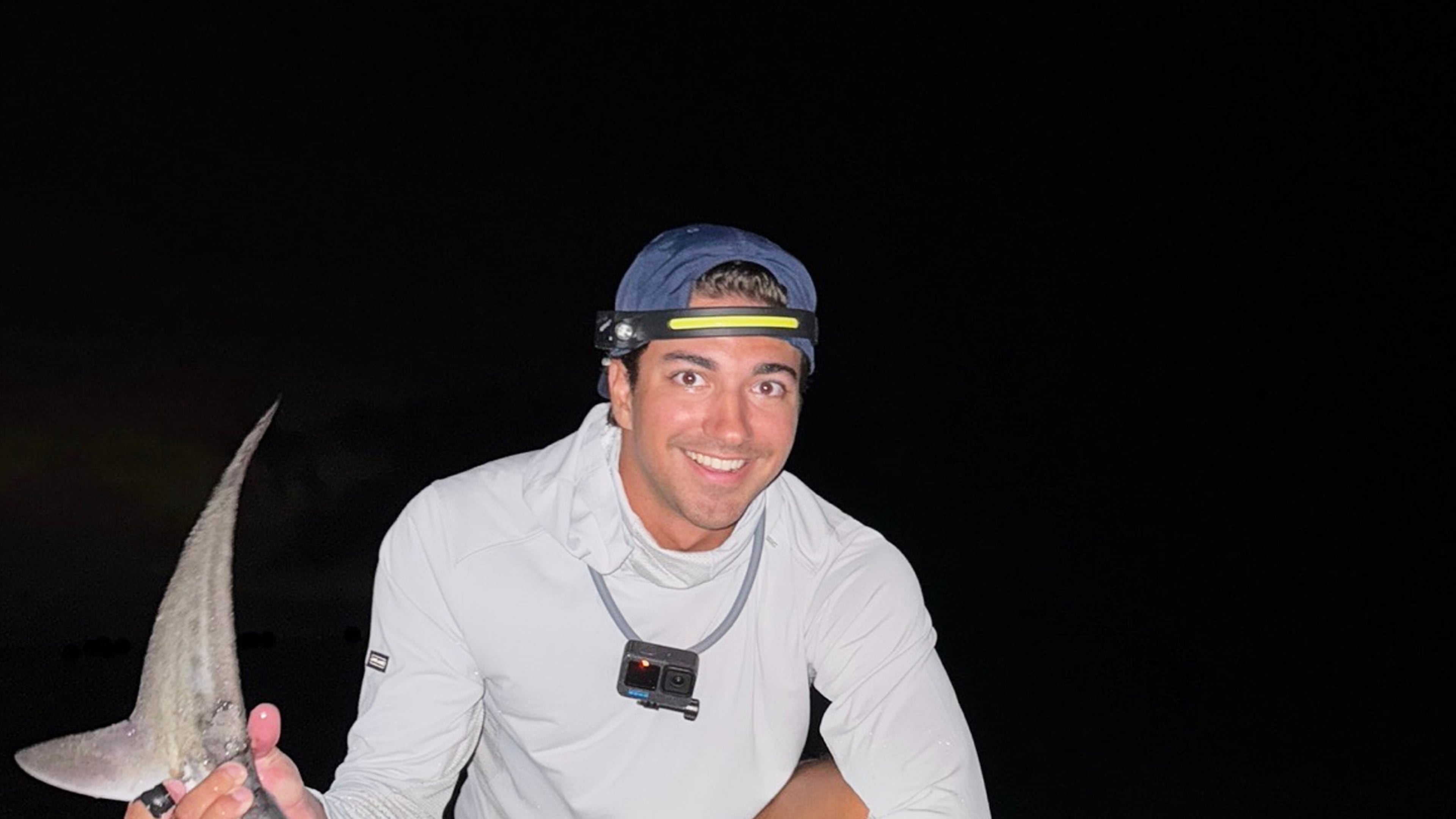 This photo provided by Nelson Rouette shows his brother, Nate Rouette, holding a young tiger shark that they caught off Falmouth Mass., July 23, 2026. (Nelson Rouette via AP)