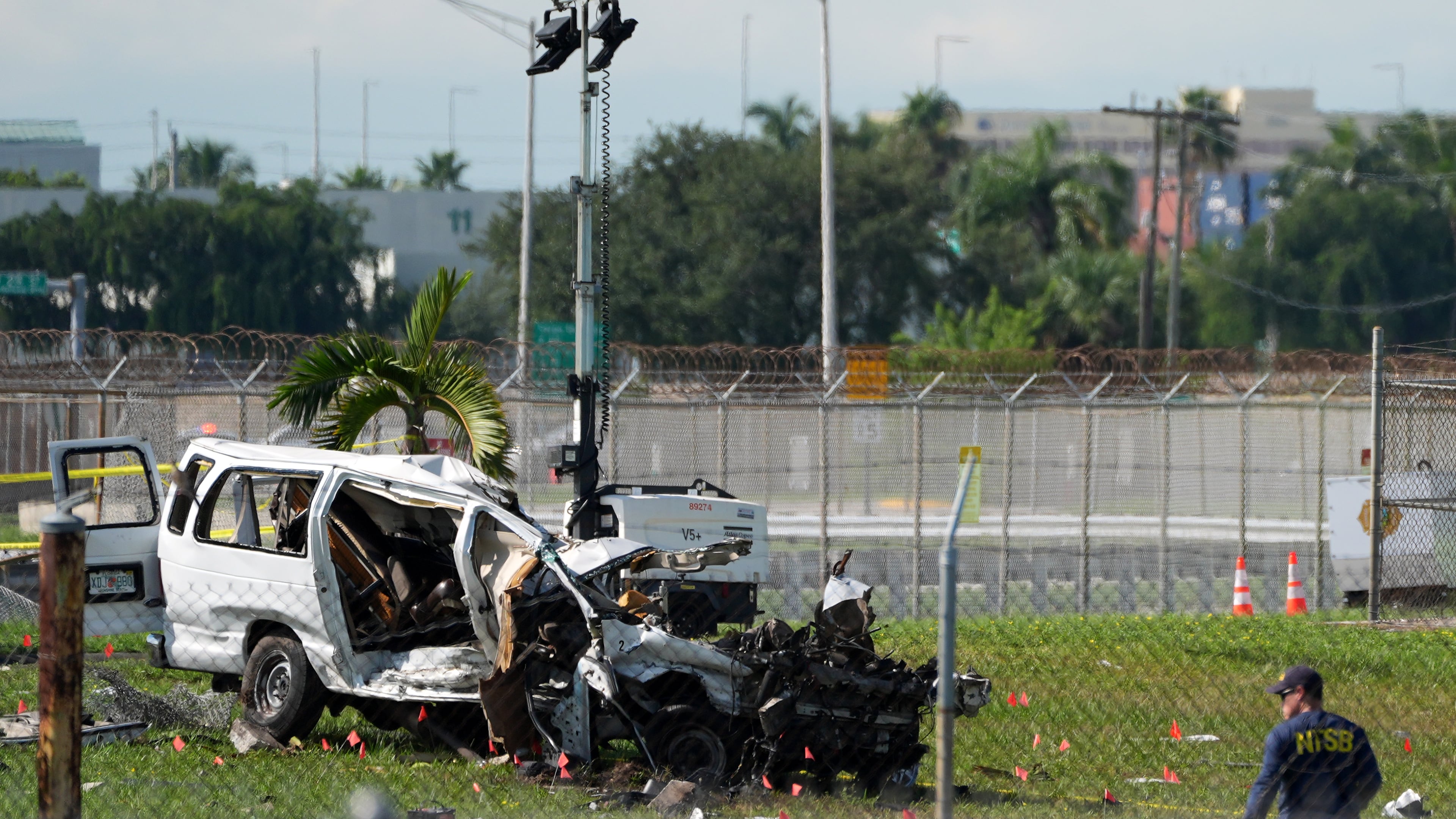 An NTSB investigator works near a damaged van at the site where an Amazon cargo plane overshot the runway two days earlier while landing at Miami International Airport, Tuesday, Sept. 8, 2026, in Miami. (AP Photo/Rebecca Blackwell)