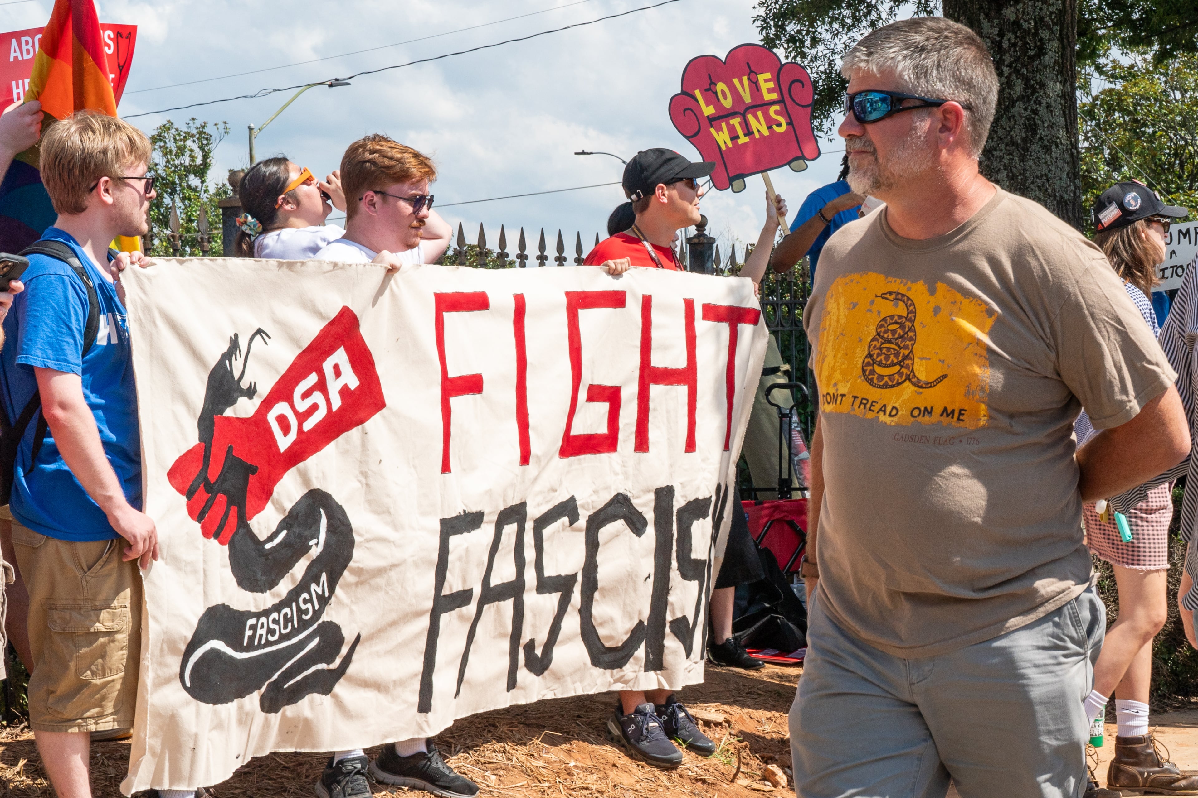 Trump rally attendees walk past a Democratic Socialists of America protest outside the Georgia State Convocation Center in Atlanta on Saturday, August 3, 2024. (Seeger Gray/AJC)