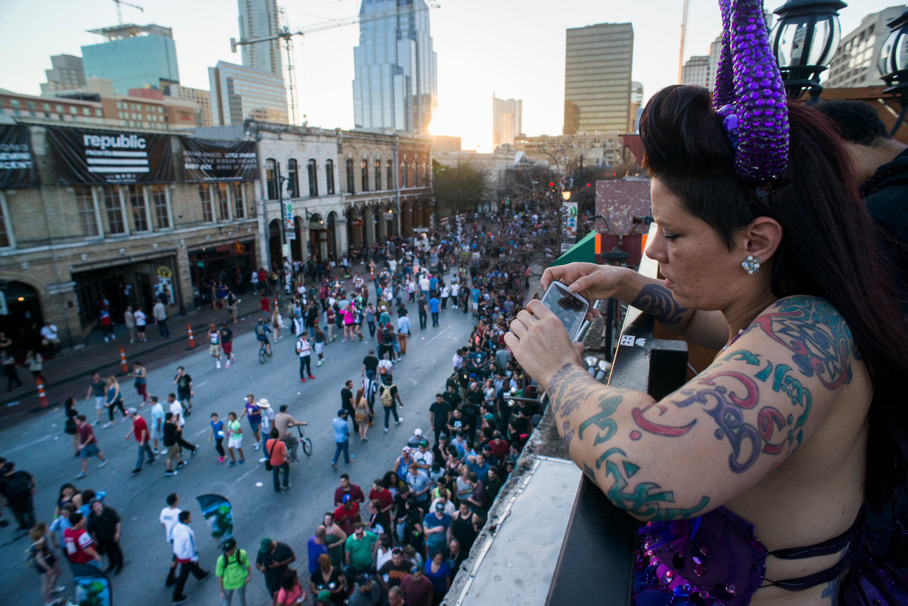 A woman uses a smartphone to take a photograph of pedestrians on 6th Street during the South By Southwest (SXSW) Interactive Festival in Austin, Texas, U.S., on Tuesday, March 11, 2014. The SXSW conferences and festivals converge original music, independent films, and emerging technologies while fostering creative and professional growth. Photographer: David Paul Morris/Bloomberg