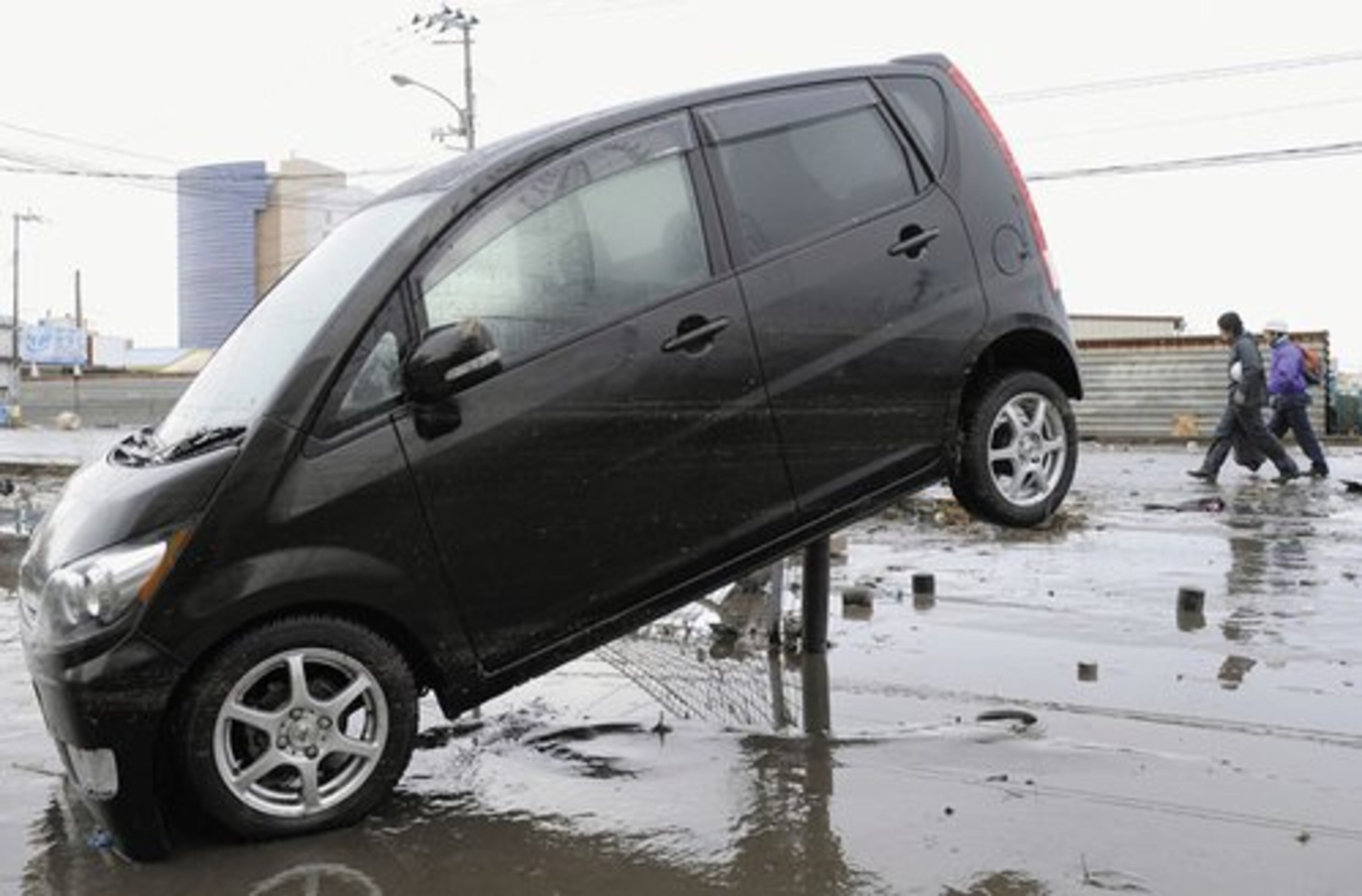 A vehicle is stranded on a steel fence after it was washed away by the tsunami in Sendai, northern Japan.