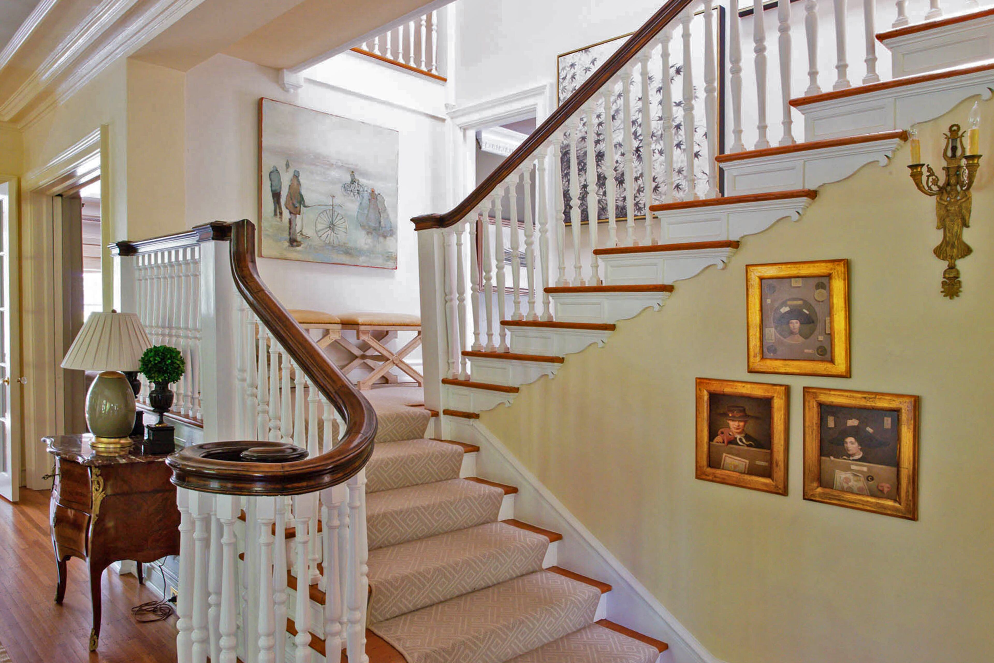 The neoclassical home's interiors include a mix of antiques and collected works of art. The trio of early 20th century paintings on wood in gold frames are from Venice. At the stair landing is an oil on linen painting by France Jodoin from Pryor Fine Art.