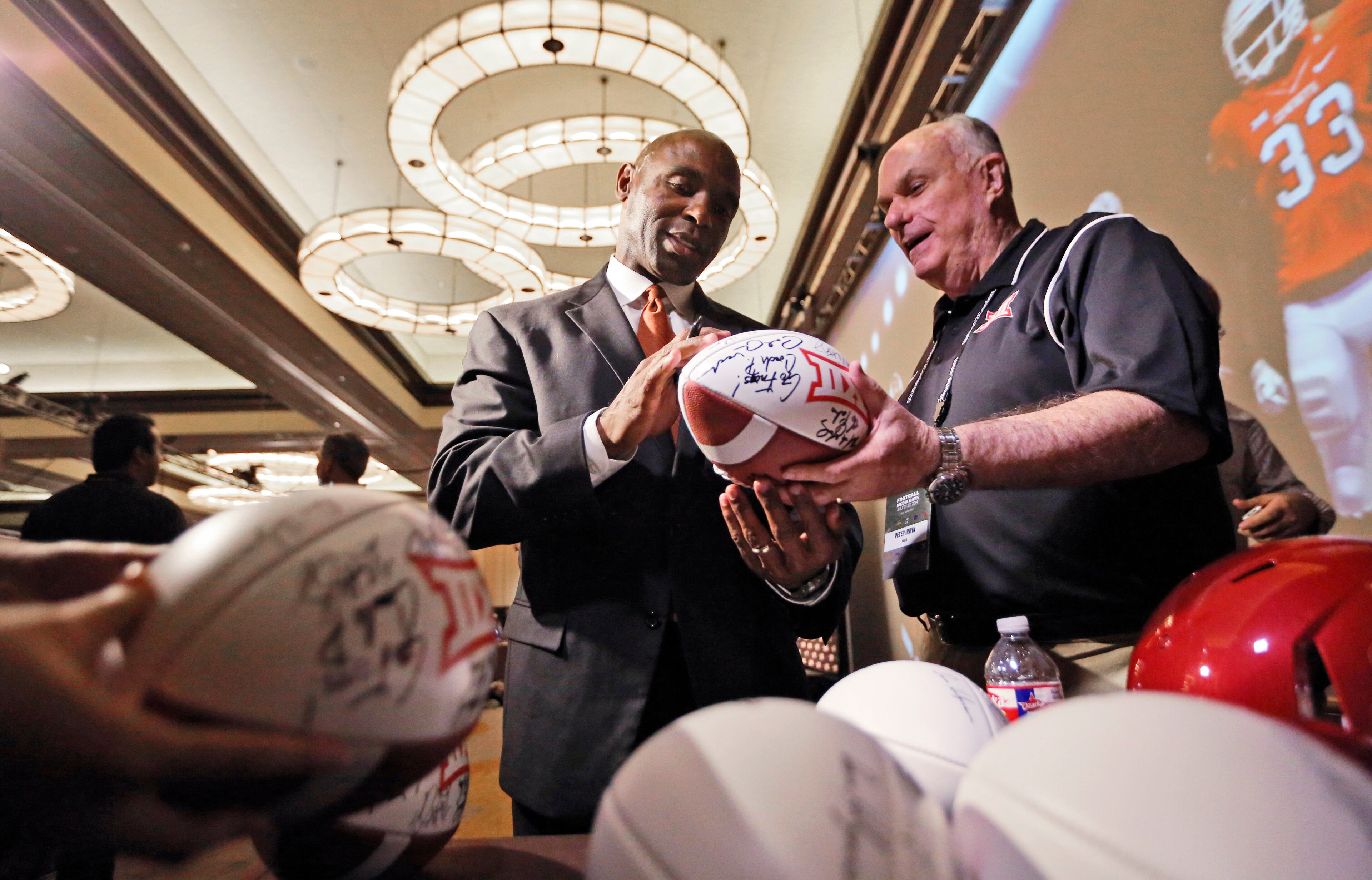 Texas head coach Charlie Strong, left, signs footballs for Peter Irwin at the Big 12 Conference NCAA college football media days in Dallas, Tuesday, July 22, 2014. (AP Photo)