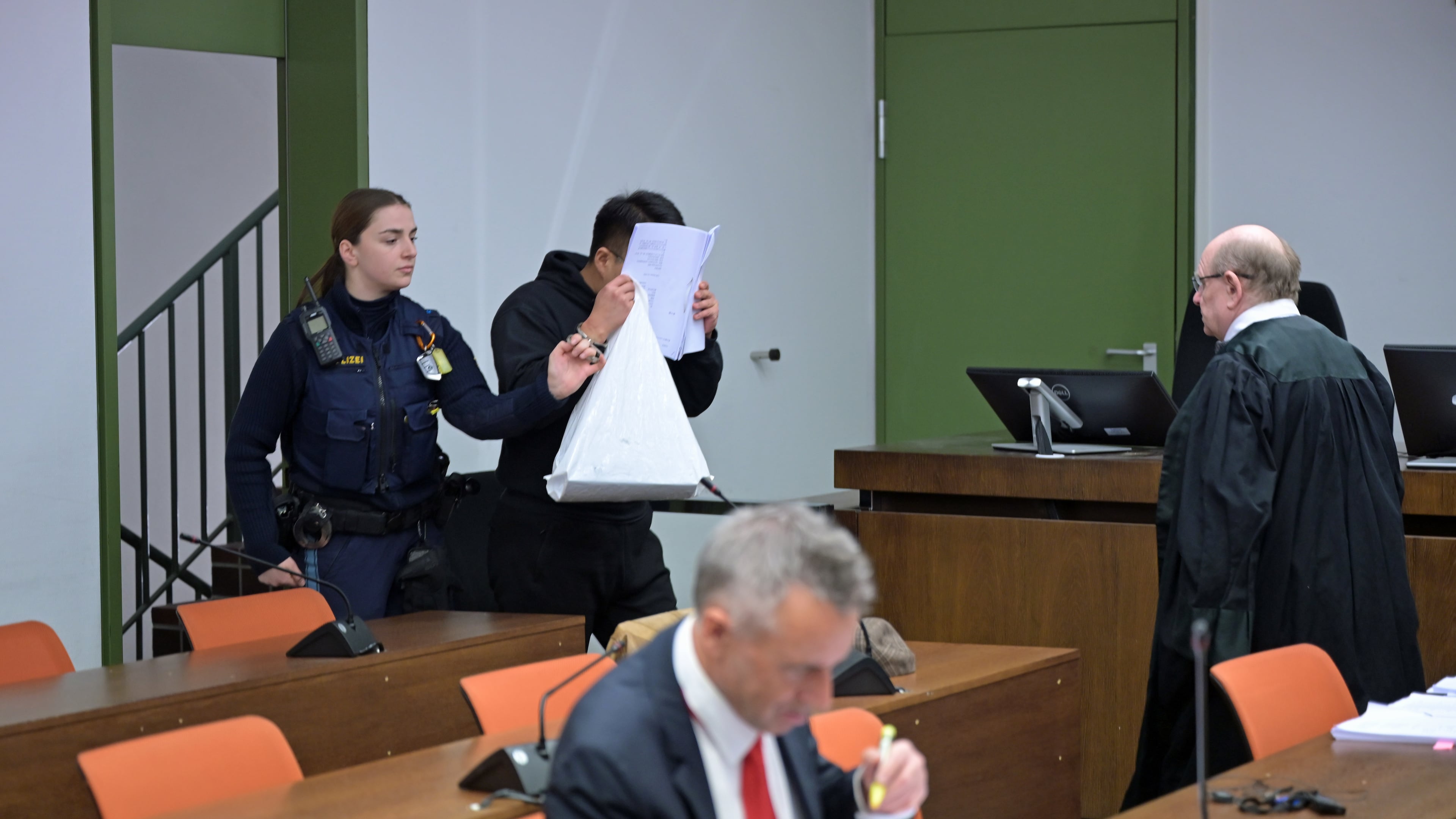 The defendant covers his face as he arrives for a trial against a network of mostly Chinese men, organized in chat groups to advise one another on how to drug and rape mostly Chinese women, in Munich, Germany, Feb. 2, 2026. (Malin Wunderlich/dpa via AP)