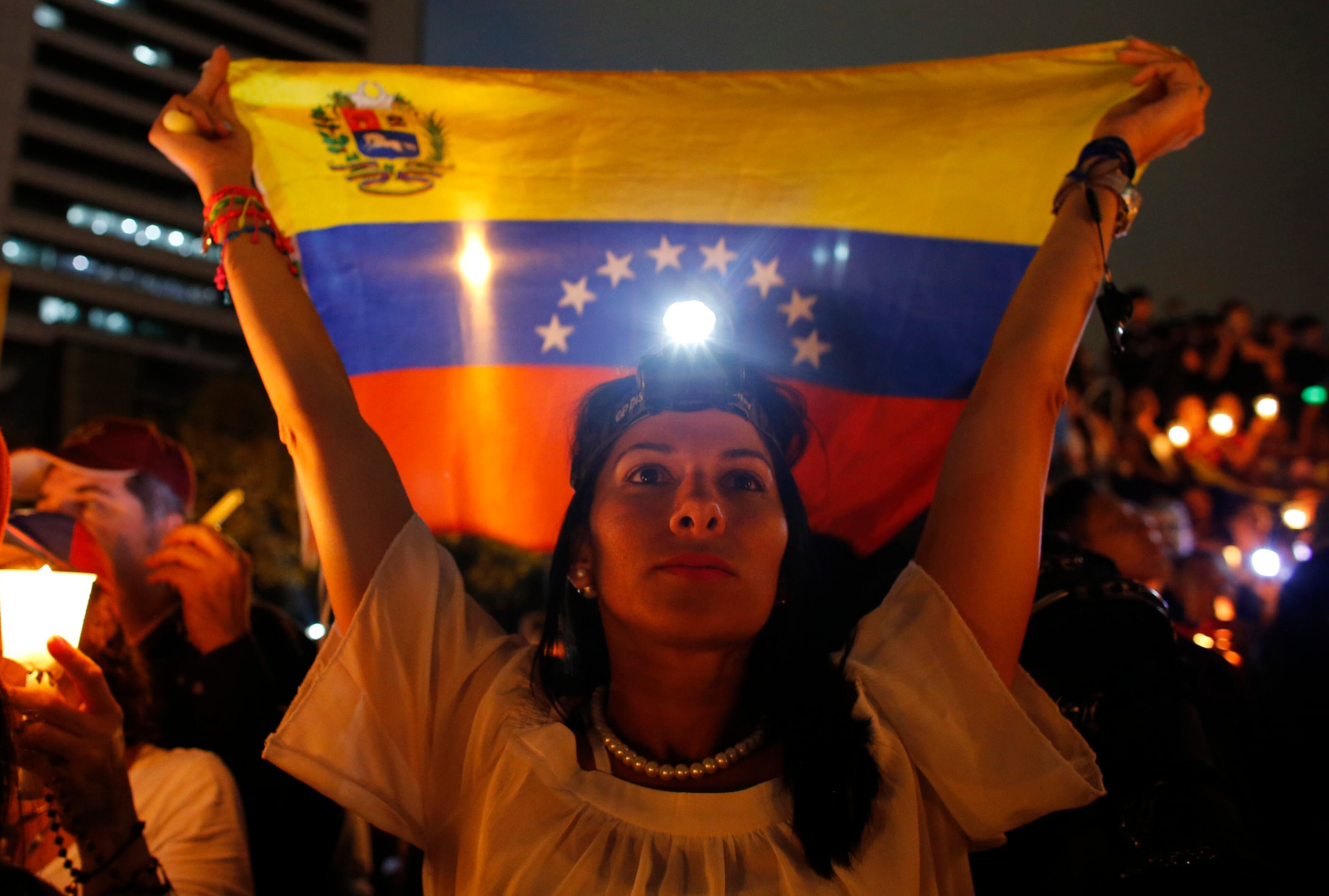 A demonstrator holds a Venezuelan flag during a vigil for the victims of the clashes with the government's security forces, during protest against President Nicolas Maduro in Caracas, Venezuela, Wednesday, May 17, 2017. Several humanitarian organizations and the opposition have accused the security forces of using too much violence during demonstrations against the government, which have left dozens dead.(AP Photo/Ariana Cubillos)