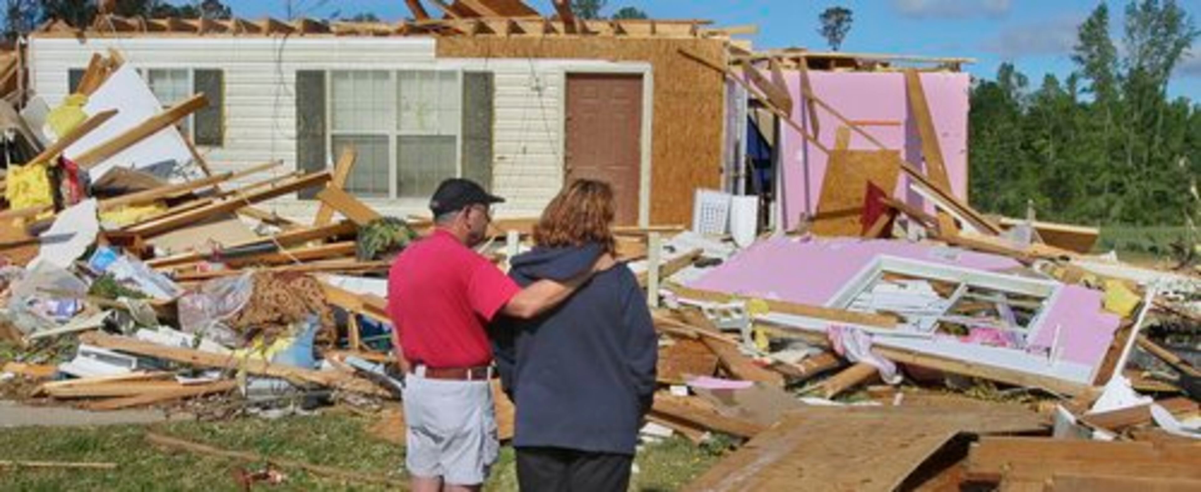 Neighbor Ken Moore comforts Stacey Peavy (right) as she looks where her 13-year daughter was sucked out of their house by a tornado -- with no serious injury.
