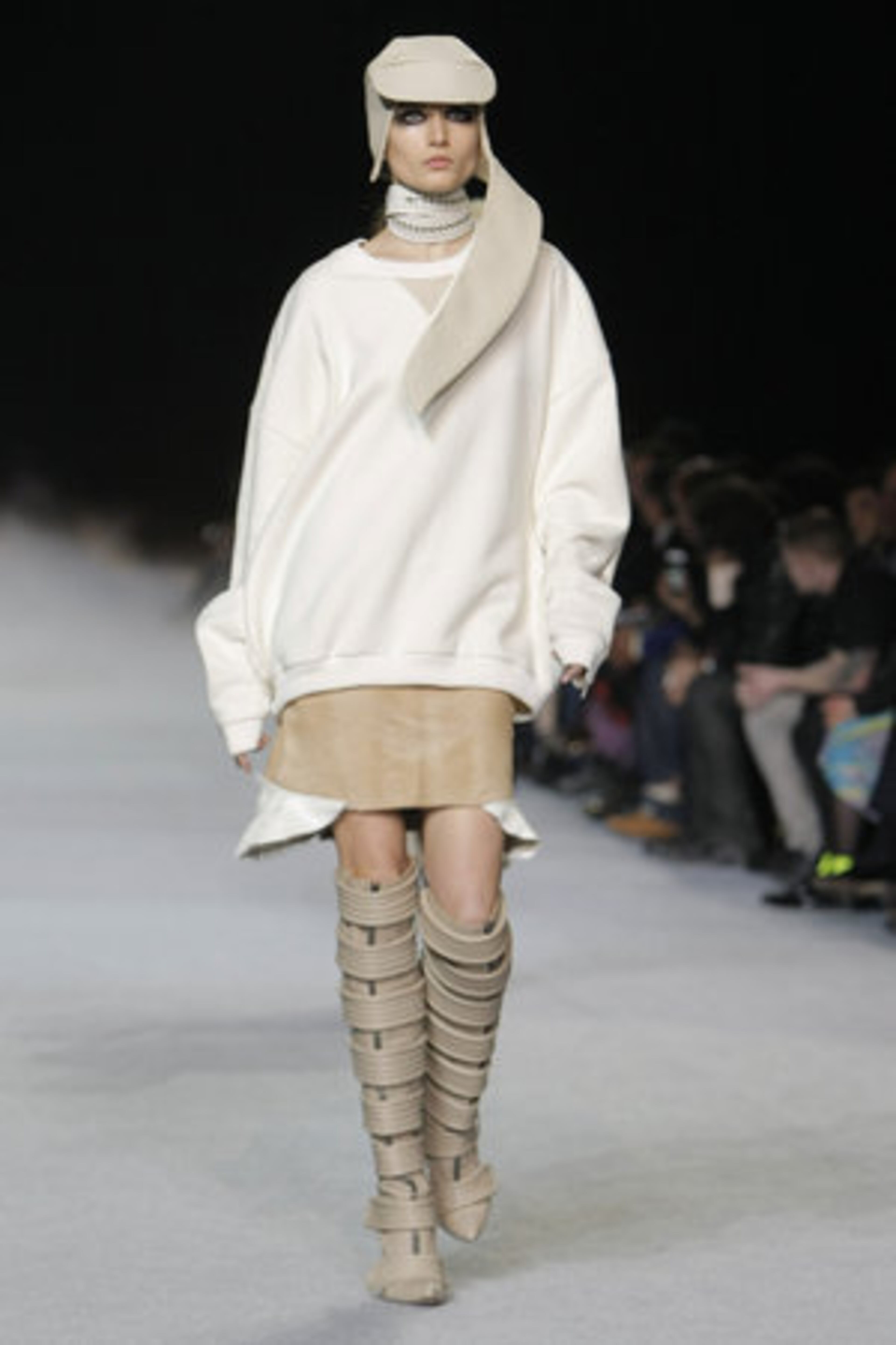An over-sized sweater and tan skirt are pumped up with knee-high strappy boots.