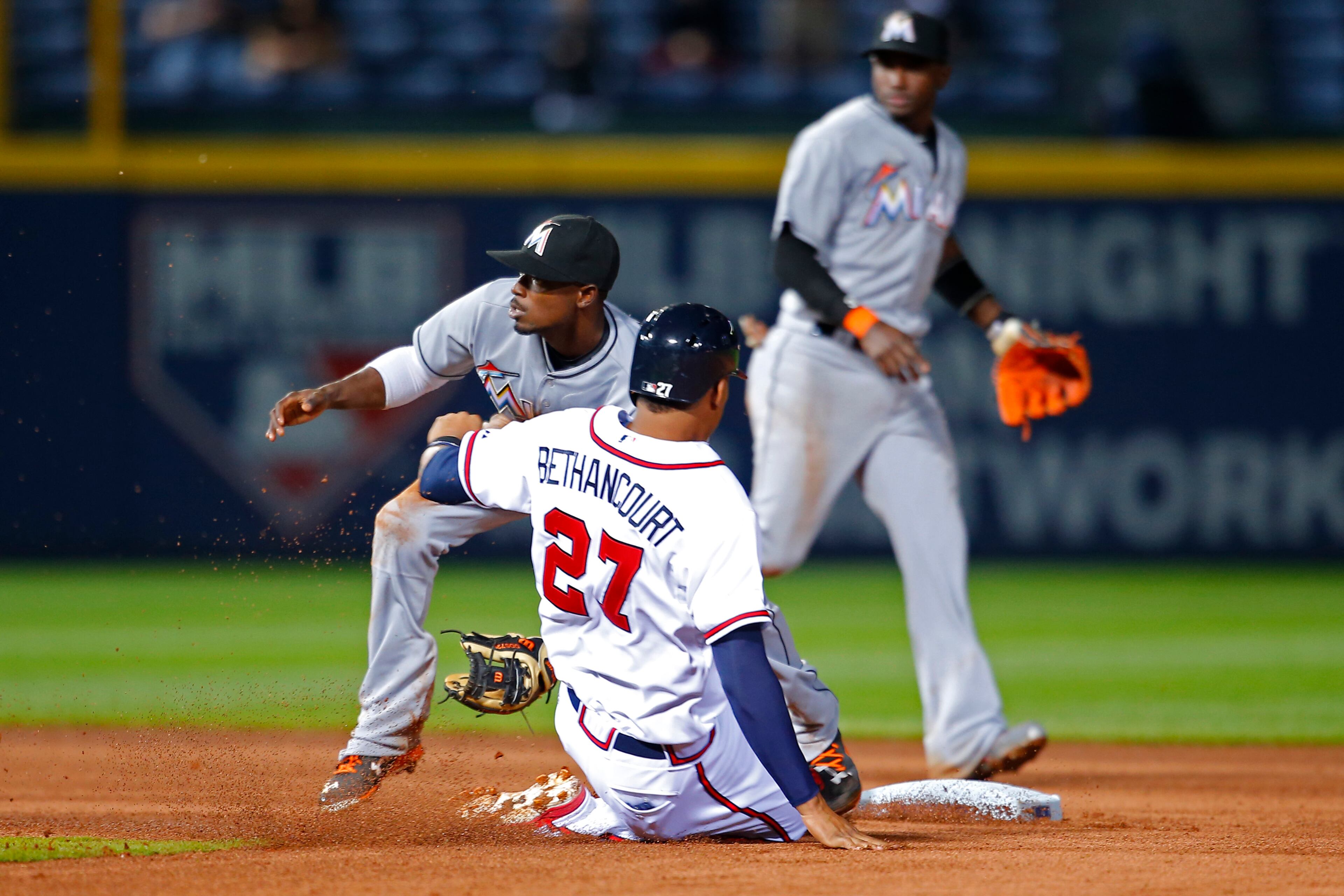 Miami Marlins second baseman Dee Gordon (9) bobbles the ball as Atlanta Braves Christian Bethancourt (27) steals second in the fourth inning of a baseball game Monday, April 13, 2015, in Atlanta. (AP Photo/Todd Kirkland)