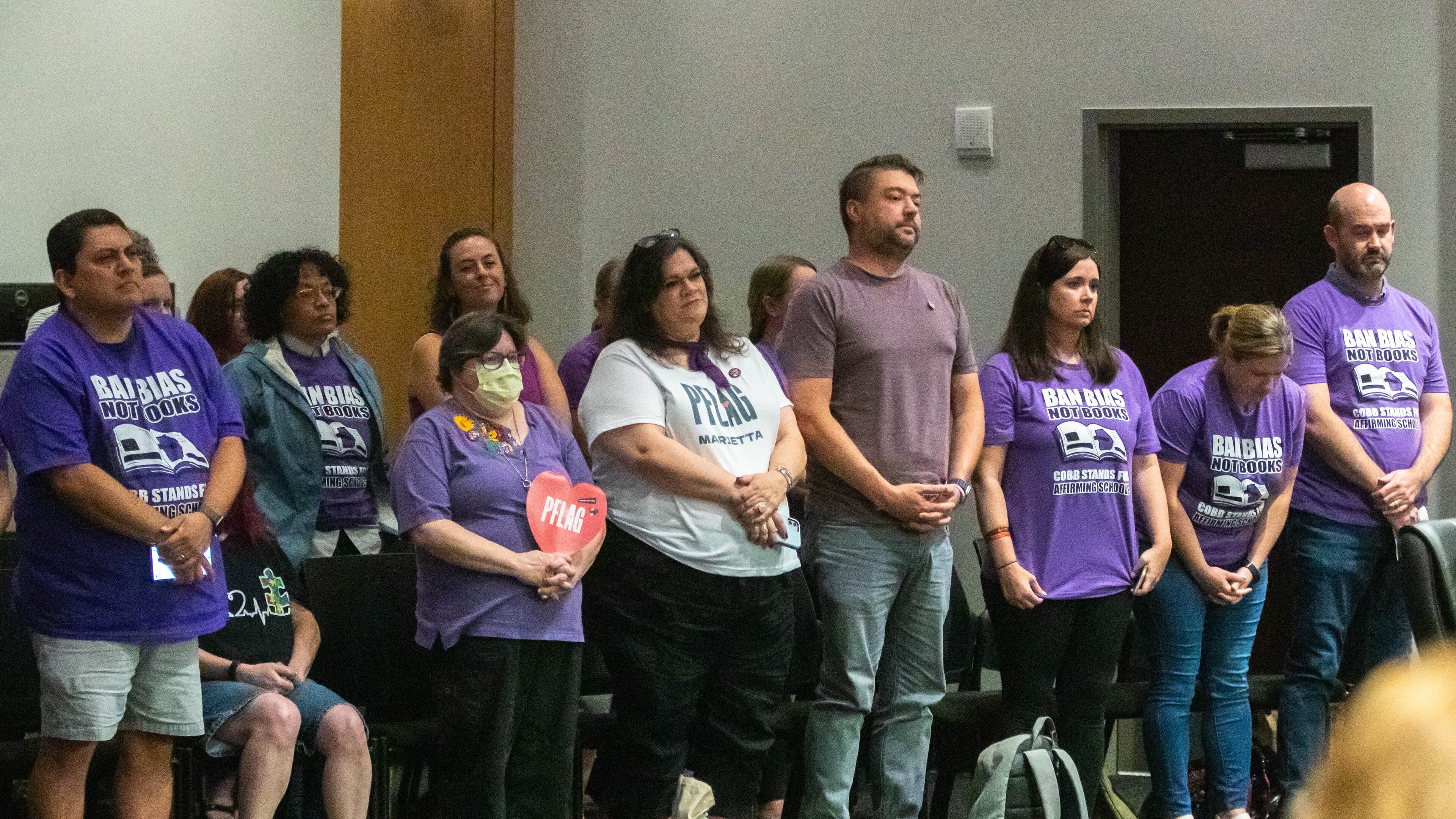 Demonstrators urged the Cobb County school board to embrace inclusivity. Speakers are not allowed to talk about issues related to employee discipline, but teacher Katie Rinderle, who read "My Shadow Is Purple" to fifth graders, and her impending termination hearing were the subtext of much of the July 20, 2023, meeting. From left (front row) are Micheal Garza, Nicole Kidwell, Erin Elwell, Kevin Redmon, Jennifer Susko, Melissa Marten, and Mike Marten. (Katelyn Myrick/katelyn.myrick@ajc.com)