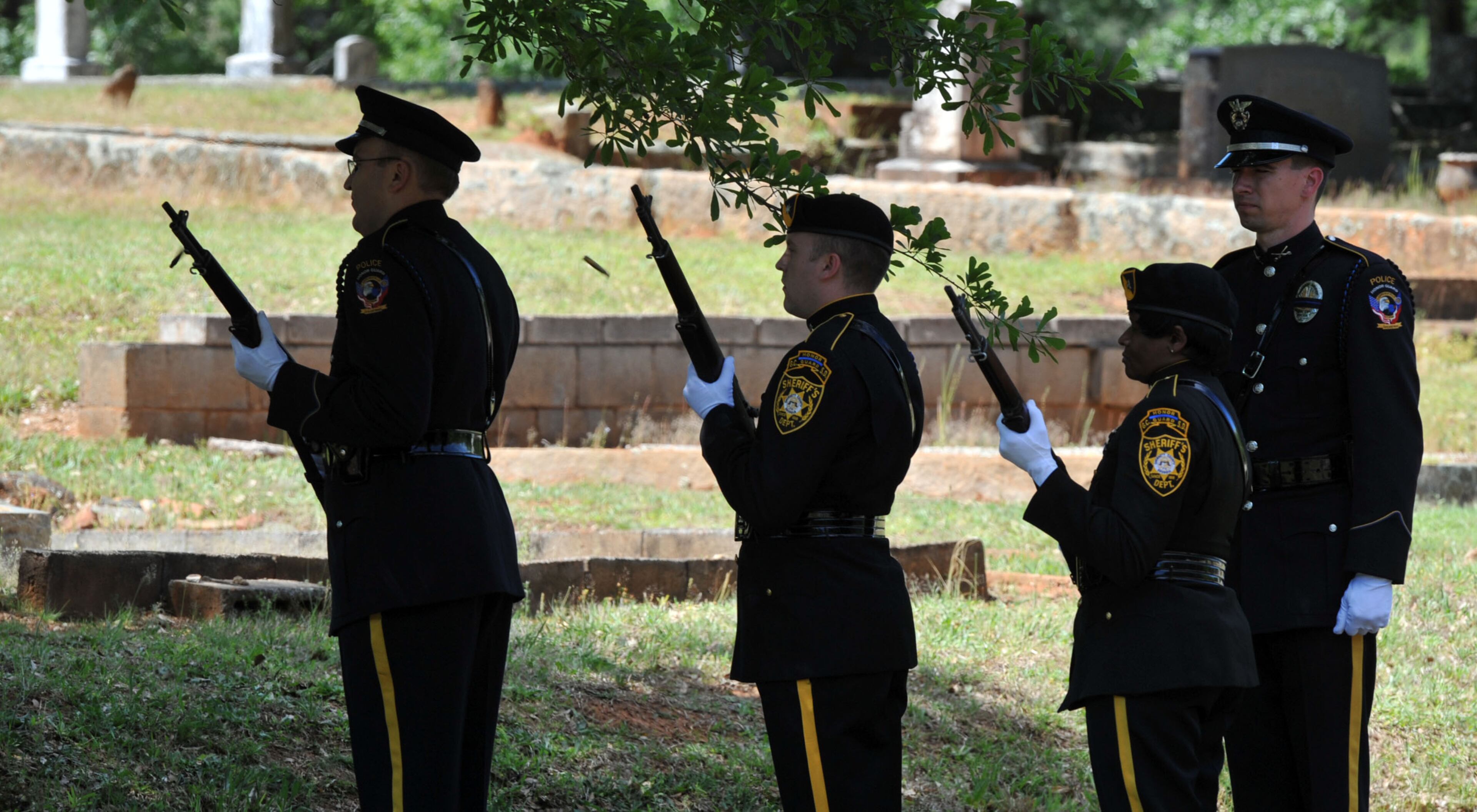 A firing squad from the Gwinnett County Sheriff's Department fires a volley in honor of Officer Hawk at the A.E. Carter Funeral Home in Madison, Ga.
