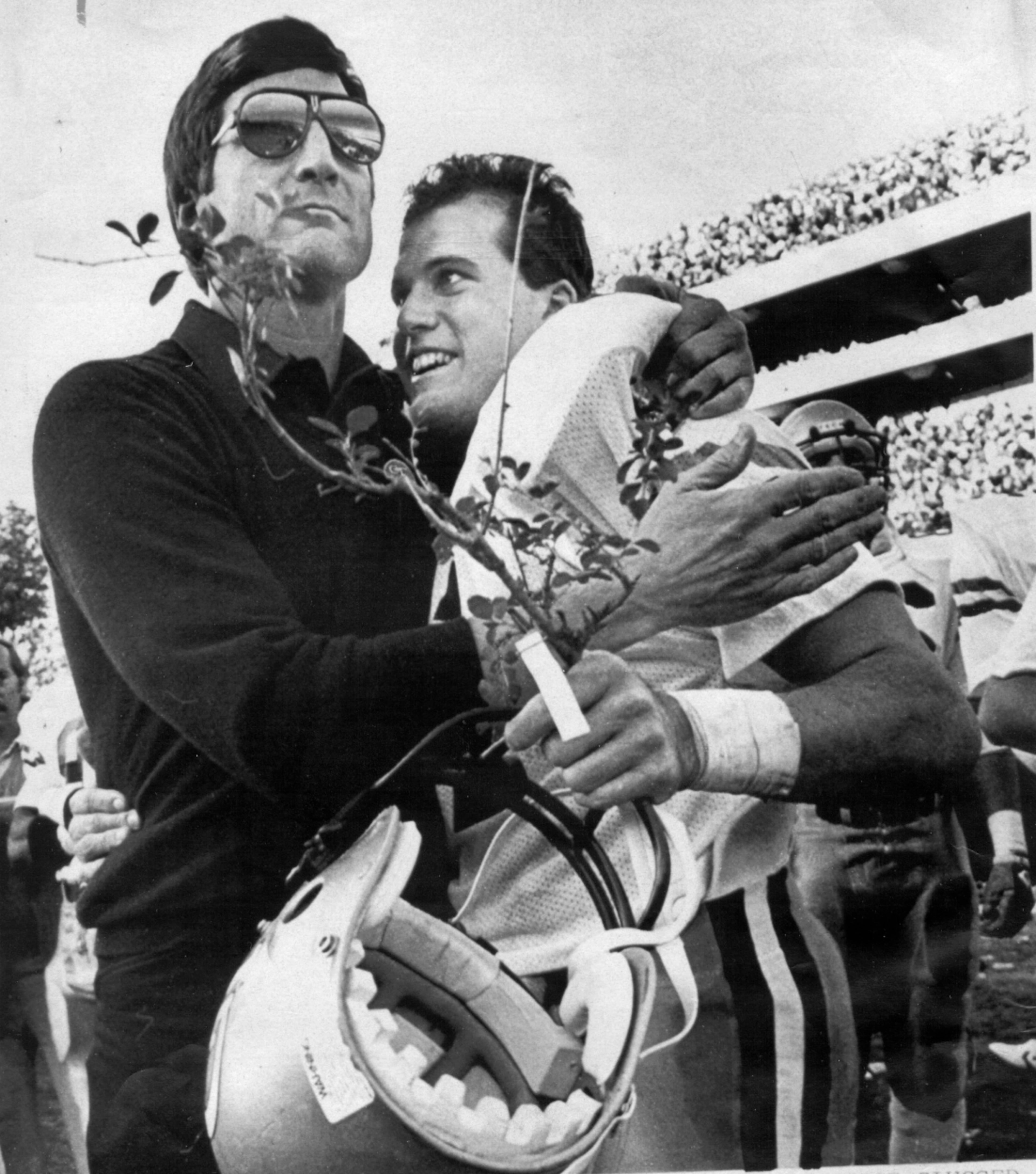 Georgia Tech quarterback John Dewberry gets a hug from coach Bill Curry and a piece of the hedge that surrounds the playing field at Sanford Stadium in Athens, following Tech's victory over Georgia in 1984. MICHAEL PUGH / AP