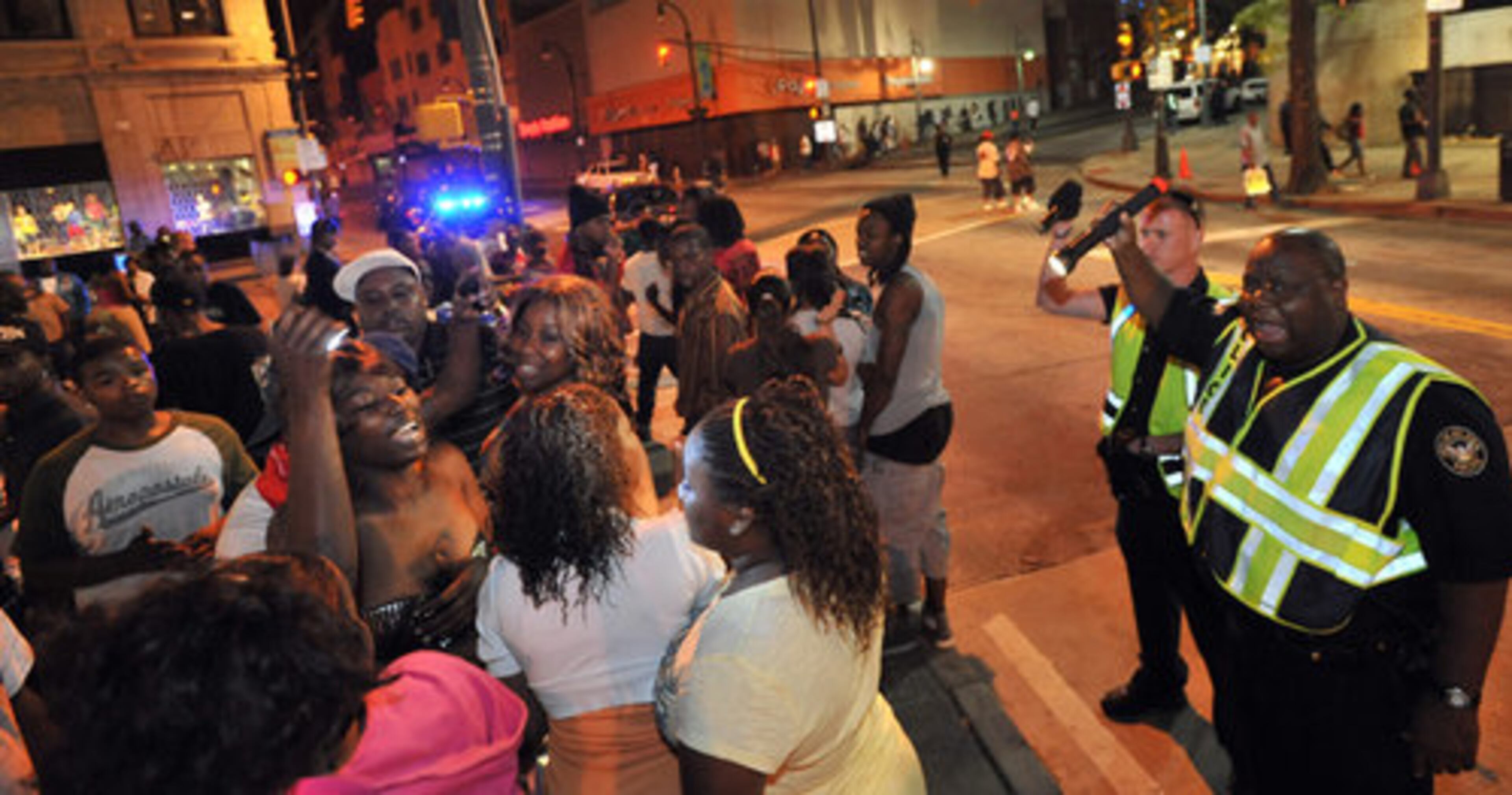 Atlanta Police officers use flashlight to keep the crowd moving.
