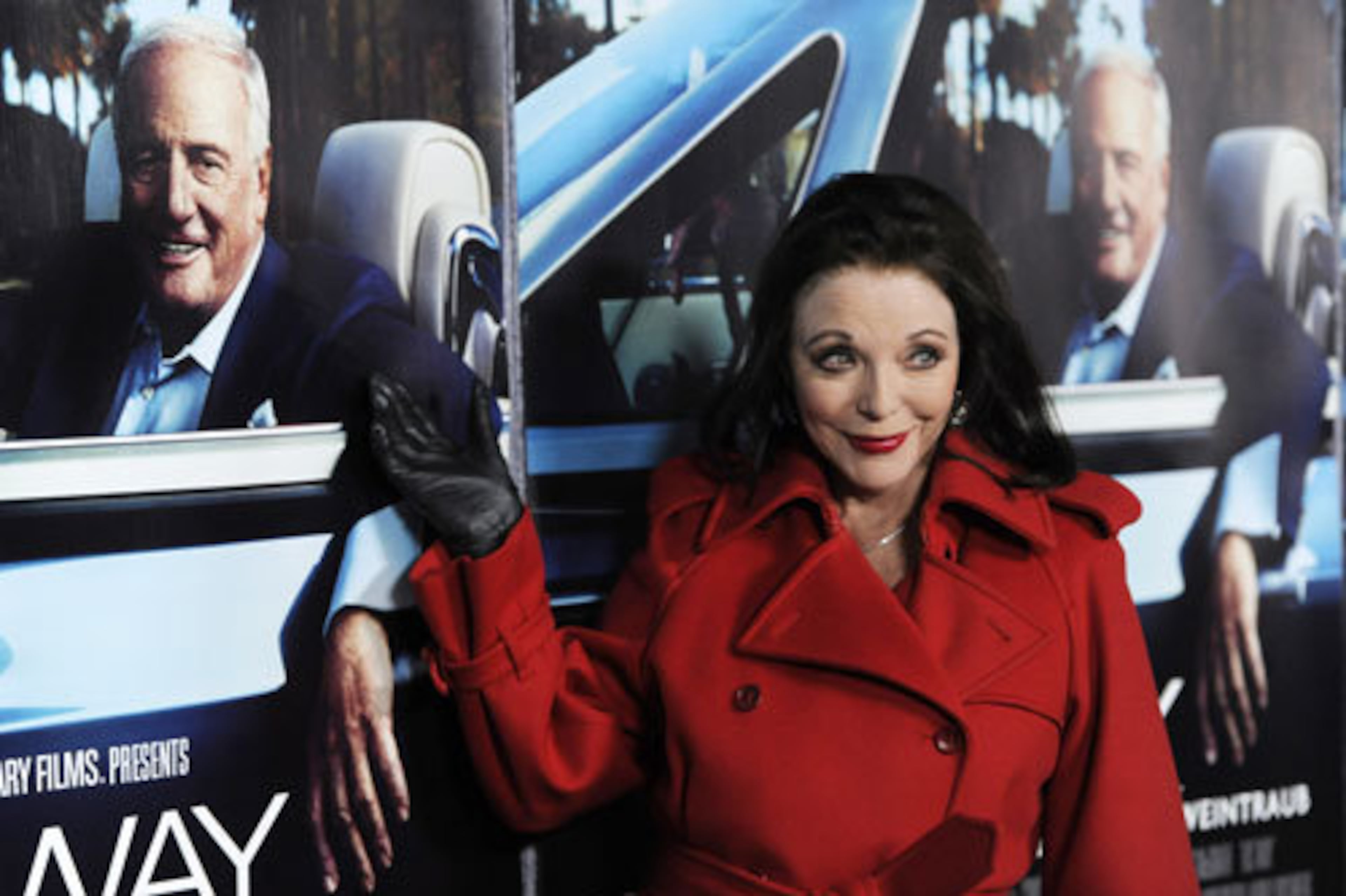 Actress Joan Collins arrives in red on the red carpet.