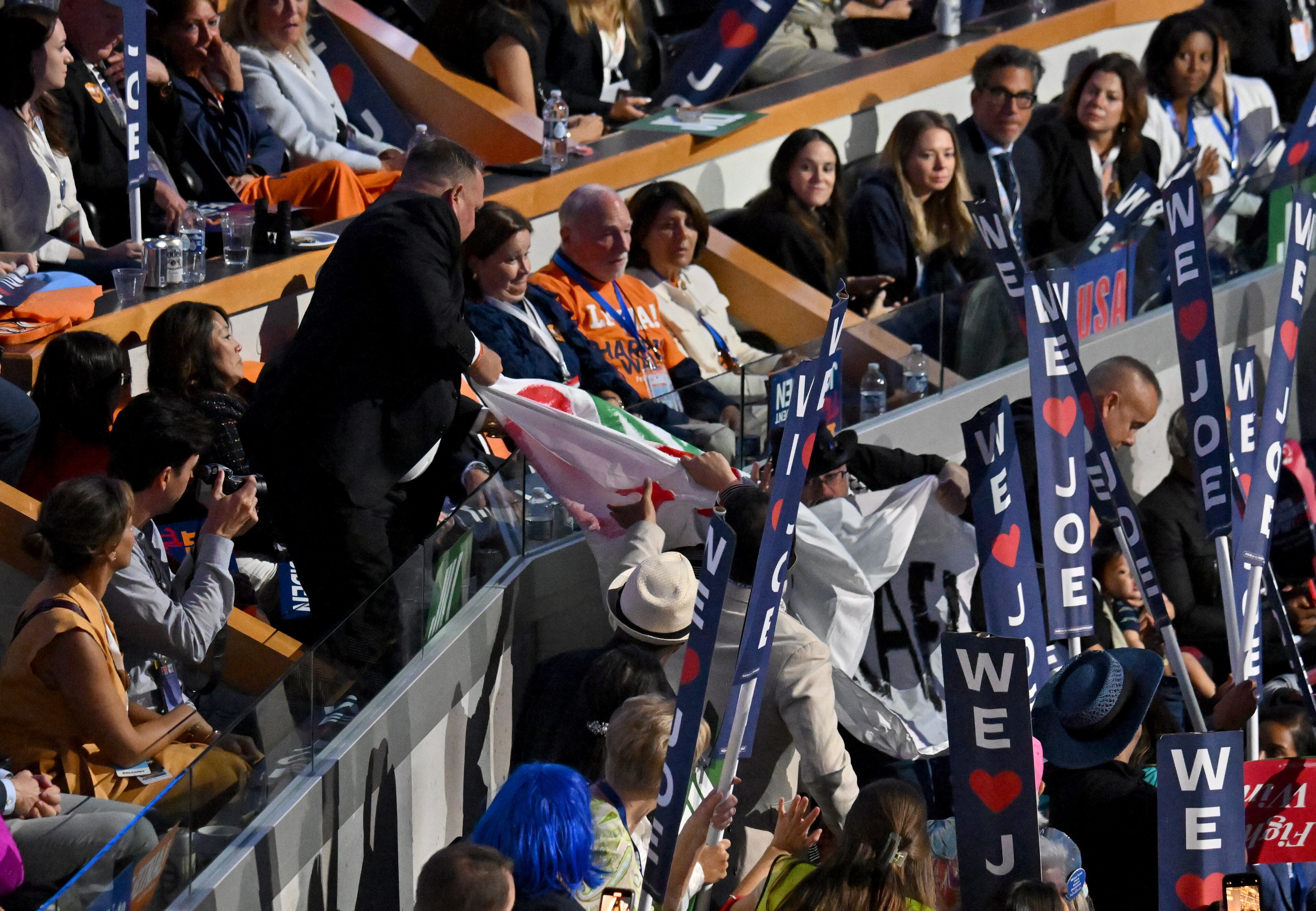 Protesters hold a sign as President Joe Biden speaks during the day 1 of the Democratic National Convention at the United Center, Monday, August 19, 2024, in Chicago, Illinois. (Hyosub Shin / AJC)