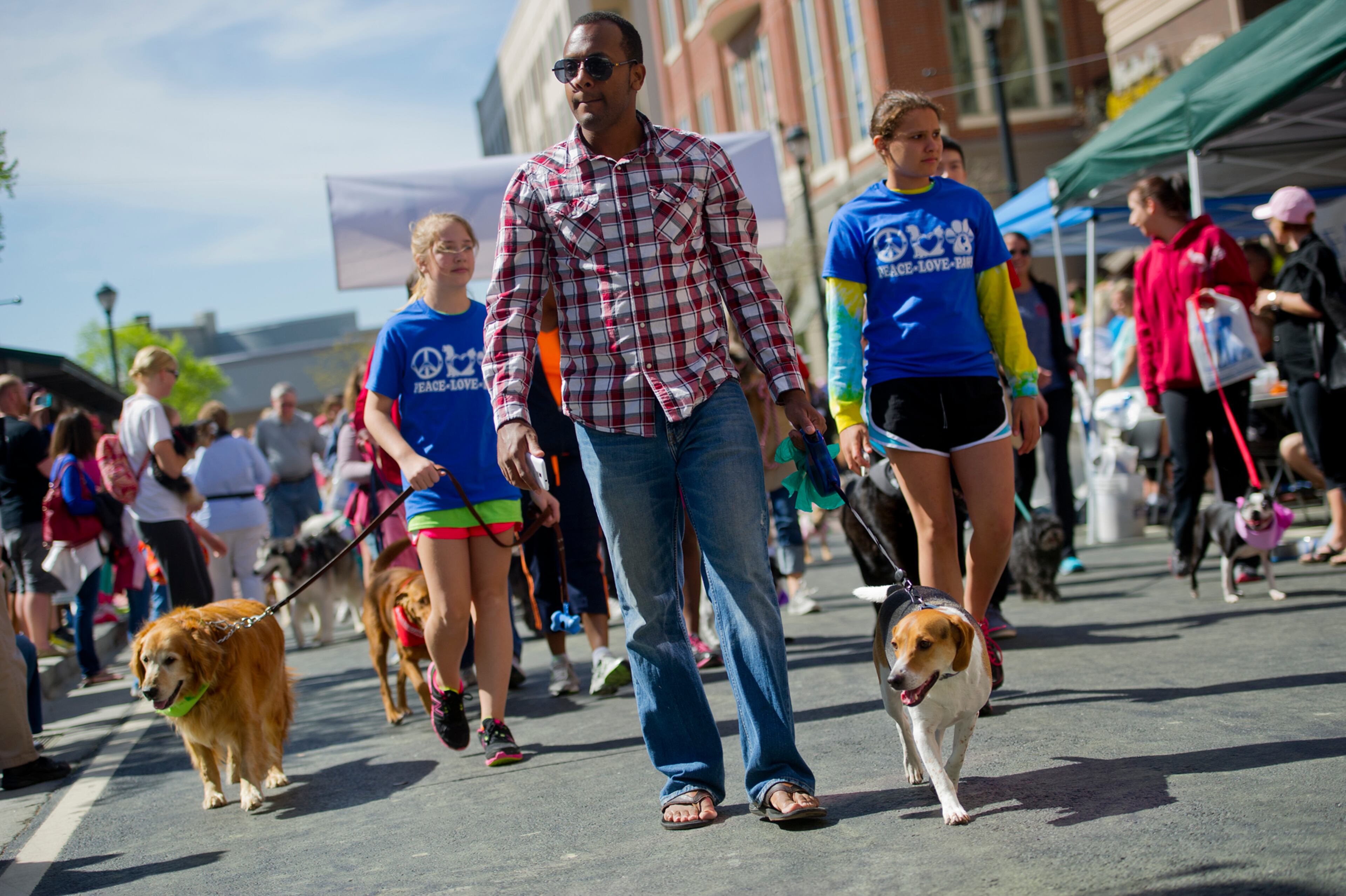 Jamie Voisin (center) walks with his dog Doegie along the route for the Atlanta Humane Society's 23rd annual Pet Parade at Atlantic Station in Atlanta Saturday, April 13, 2013. Hundreds of pets and their owners participated in the parade which helps generate awareness in the community and support fundraising for animal shelters. On average, it costs the Atlanta Humane Society approximately $300 to find a home for the each animal in their care. JONATHAN PHILLIPS / SPECIAL