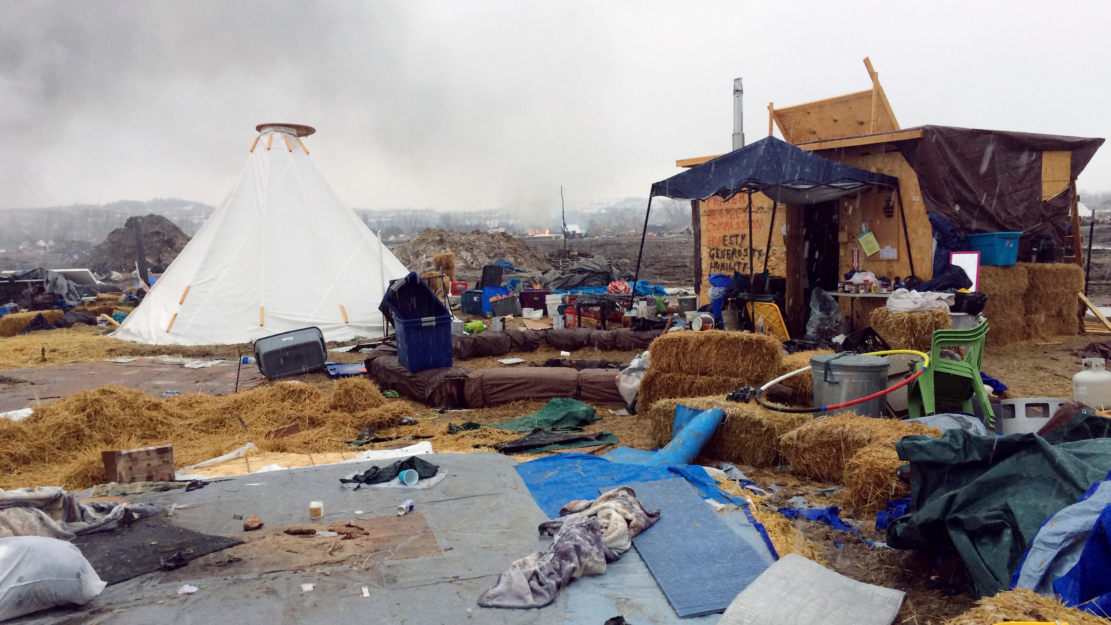 Refuse remains in the Dakota Access pipeline opponents' main protest camp as a fire burns in the background in southern North Dakota near Cannon Ball, N.D., on Wednesday, Feb. 22, 2017, as authorities prepare to shut down the camp in advance of spring flooding season. (AP Photo/Blake Nicholson)